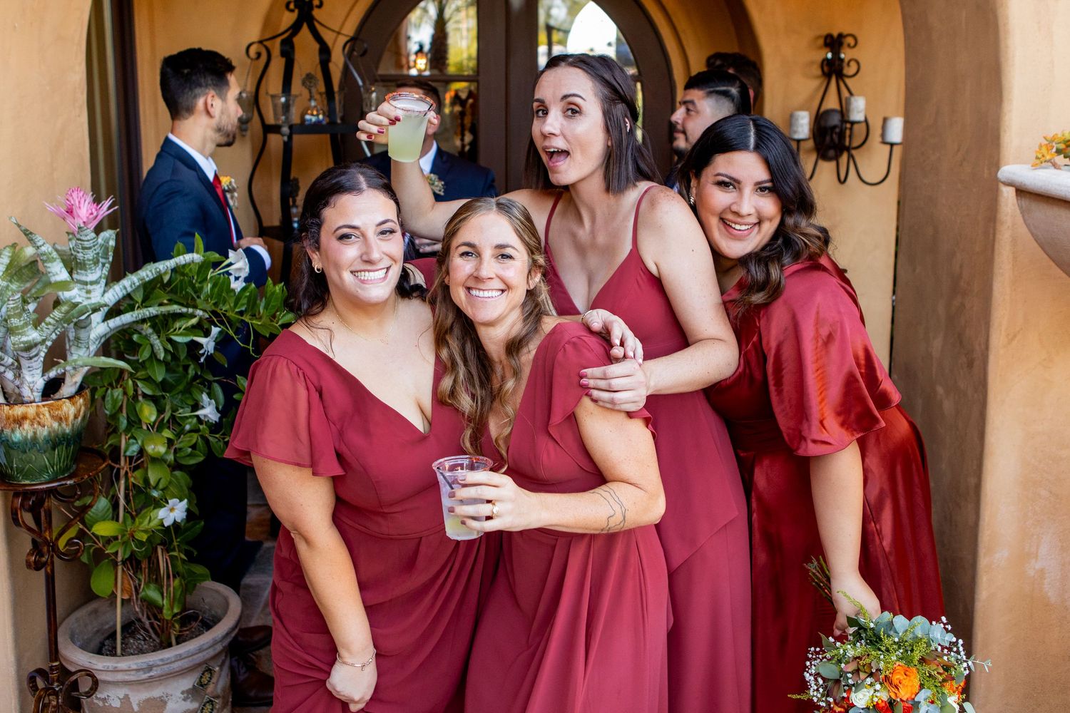 Bridesmaids in burgundy dresses gather for a celebratory moment.