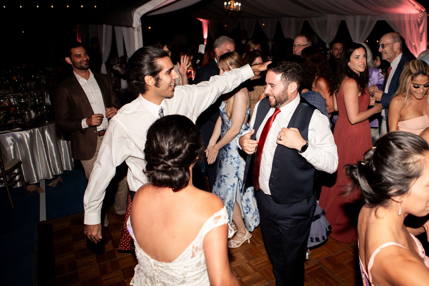 Wedding reception dance floor filled with energetic guests celebrating with bride in strapless gown.