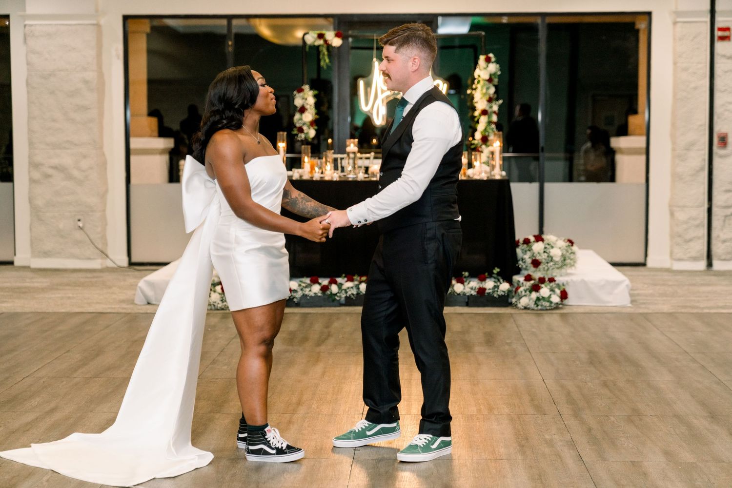 Couple in wedding attire sharing a moment on wooden dance floor.