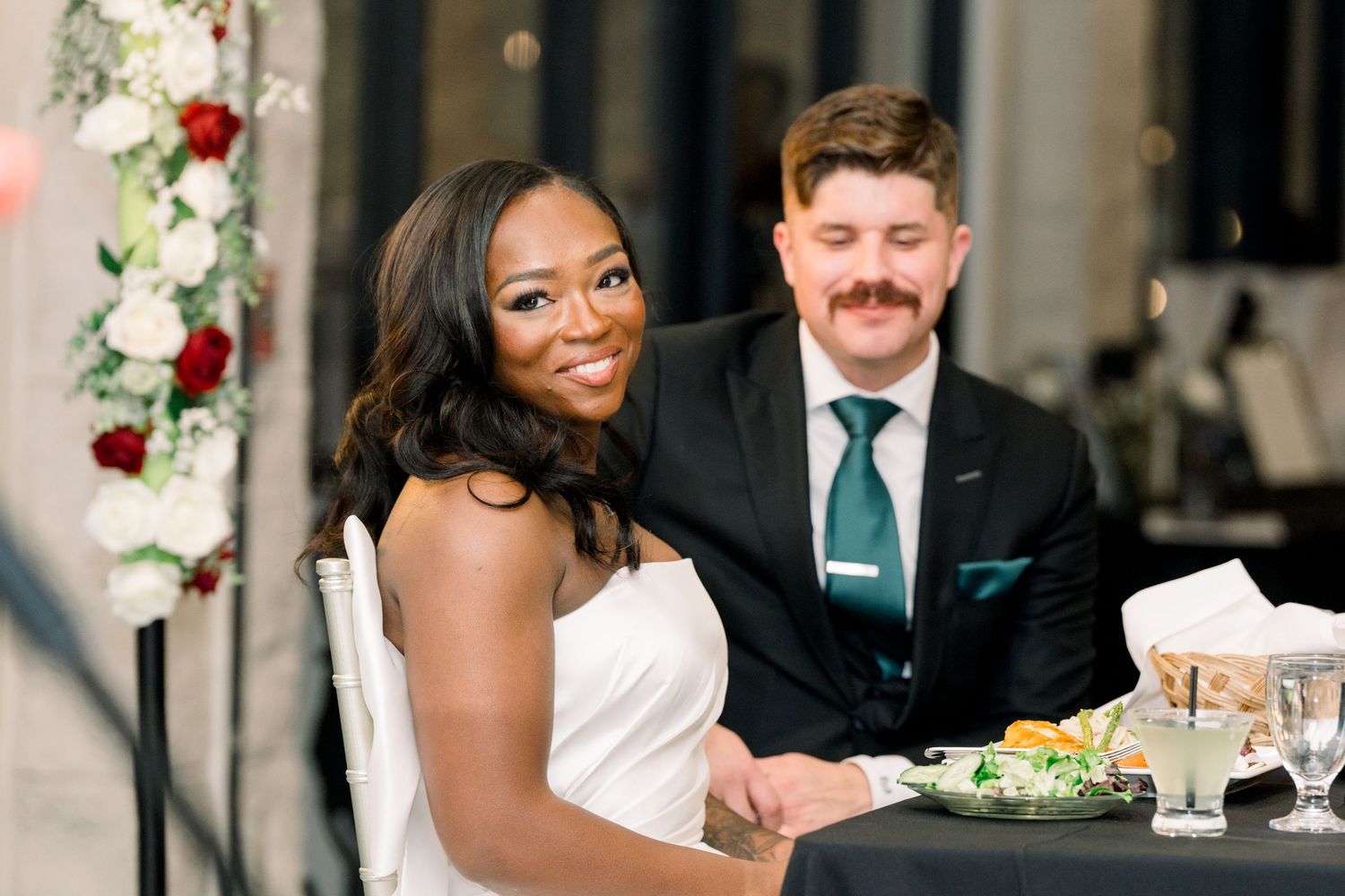 Newlyweds sharing an intimate moment at their reception dinner table.