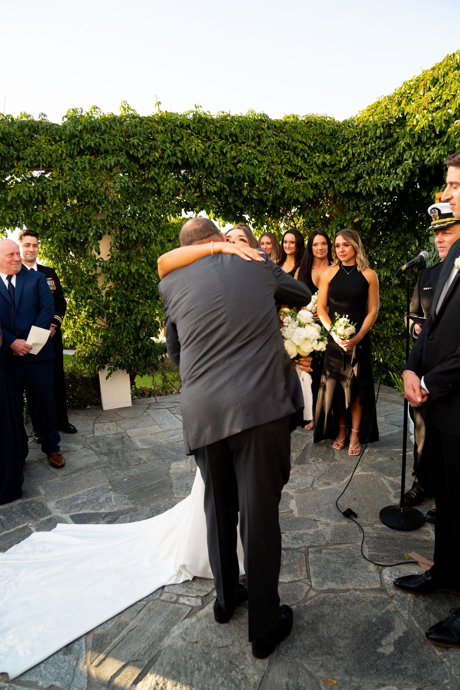 Wedding ceremony moment captured in an outdoor garden setting with stone flooring and ivy covered walls.