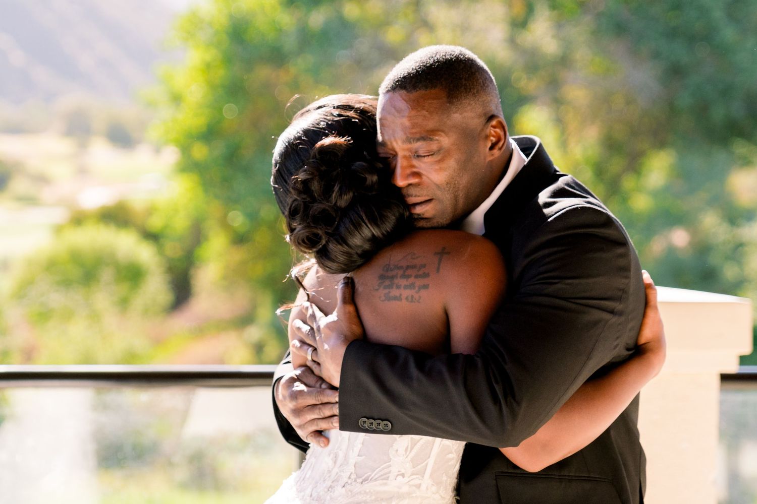 Emotional embrace between couple during wedding ceremony with mountain backdrop.
