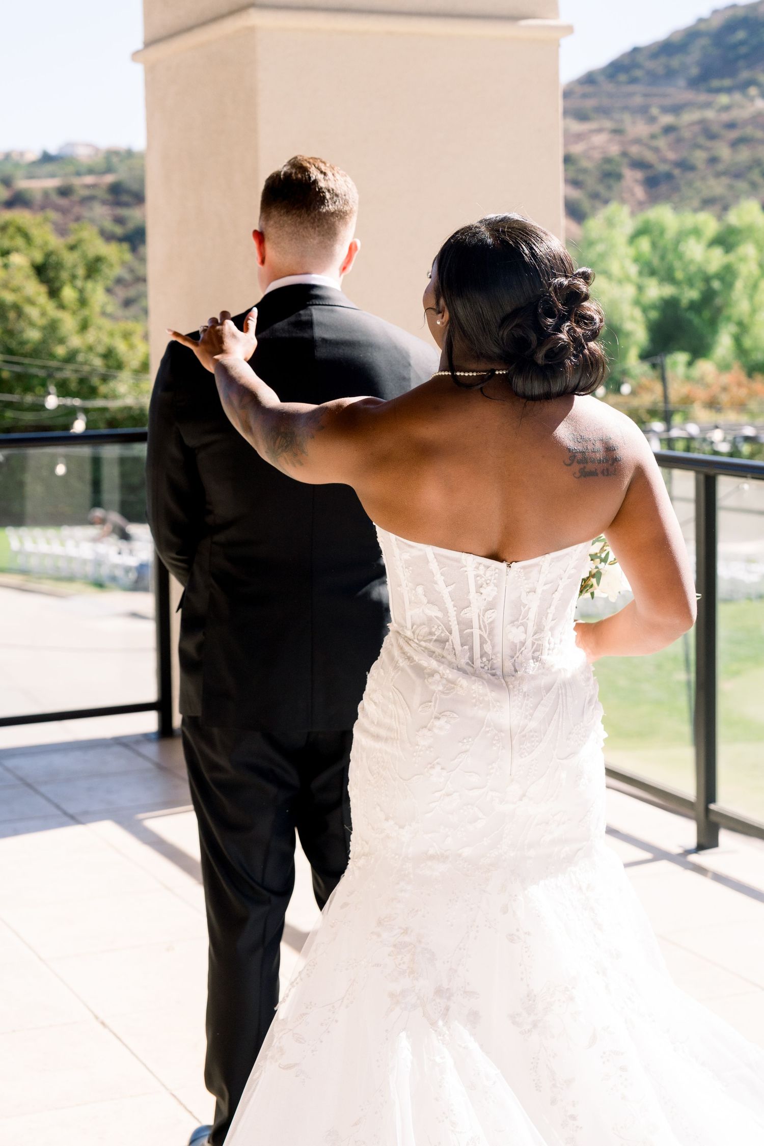 Wedding couple standing on balcony overlooking mountain landscape.