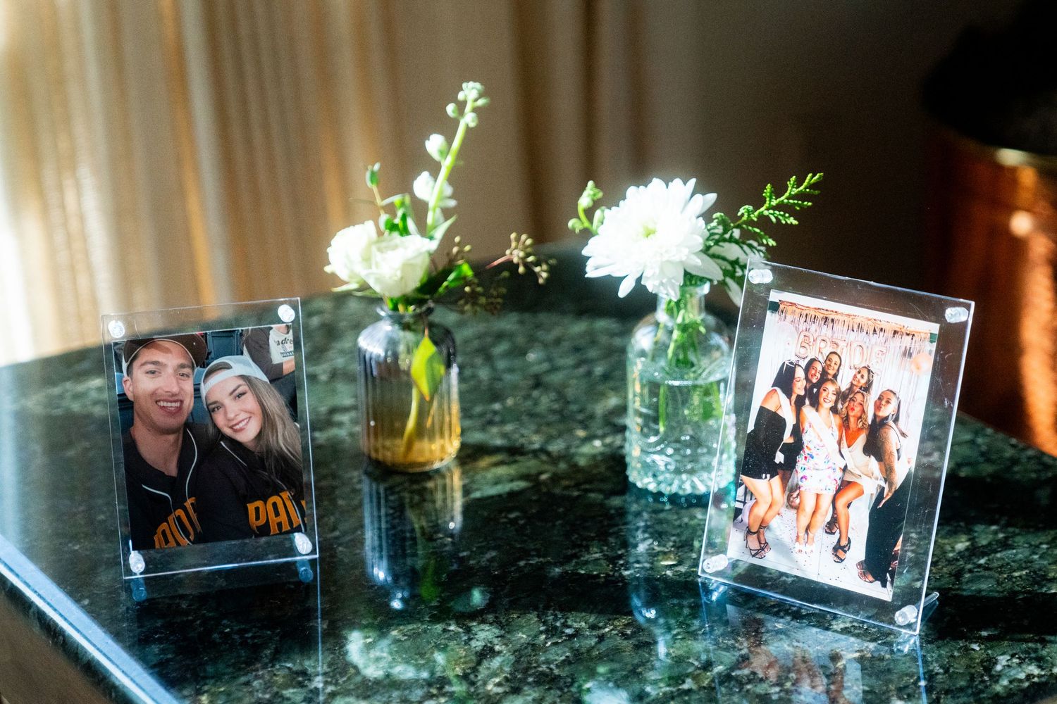 Wedding memorabilia display with framed photos and flower vases on marble surface.