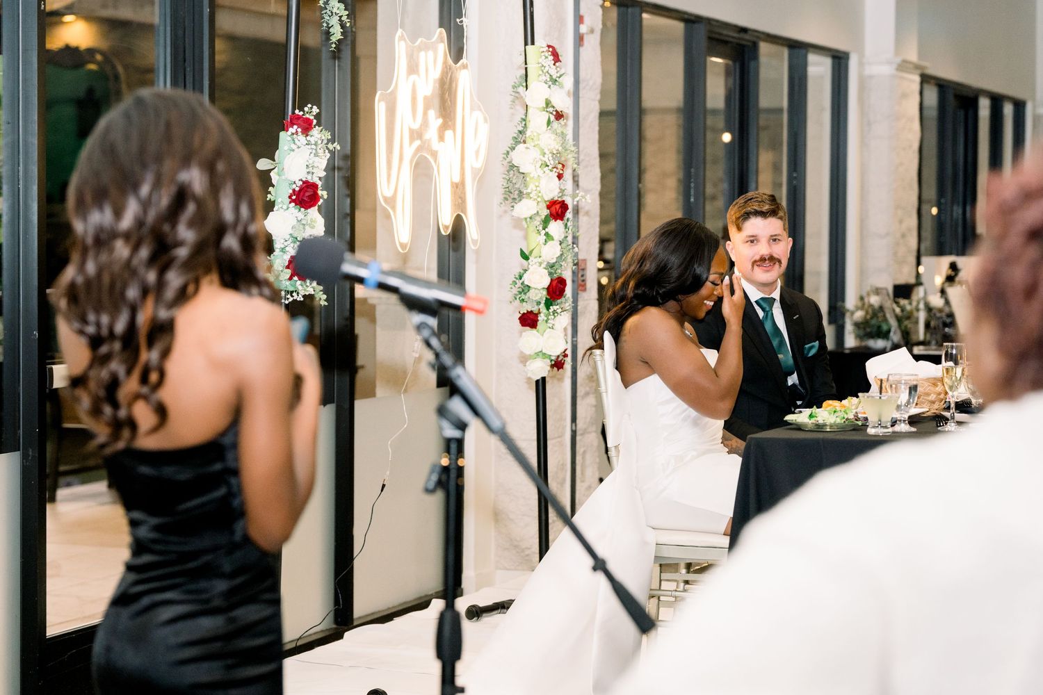 Wedding reception scene with elegant decor and floral arrangements in a mirrored venue space.