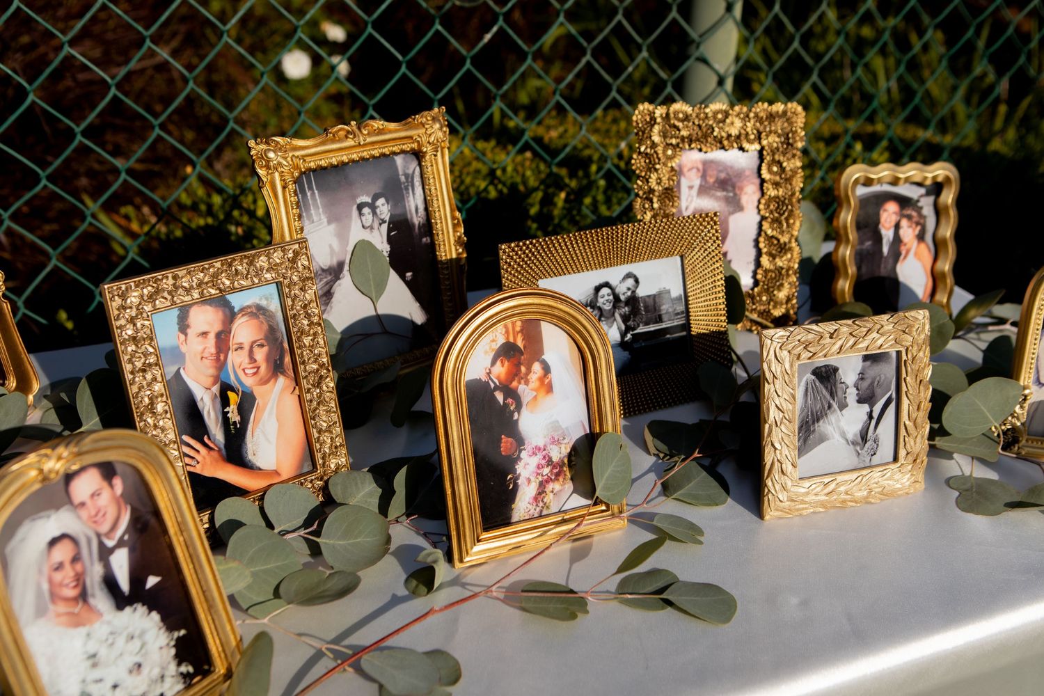 Vintage-style gold frames display cherished family photos on a decorated wedding reception table.