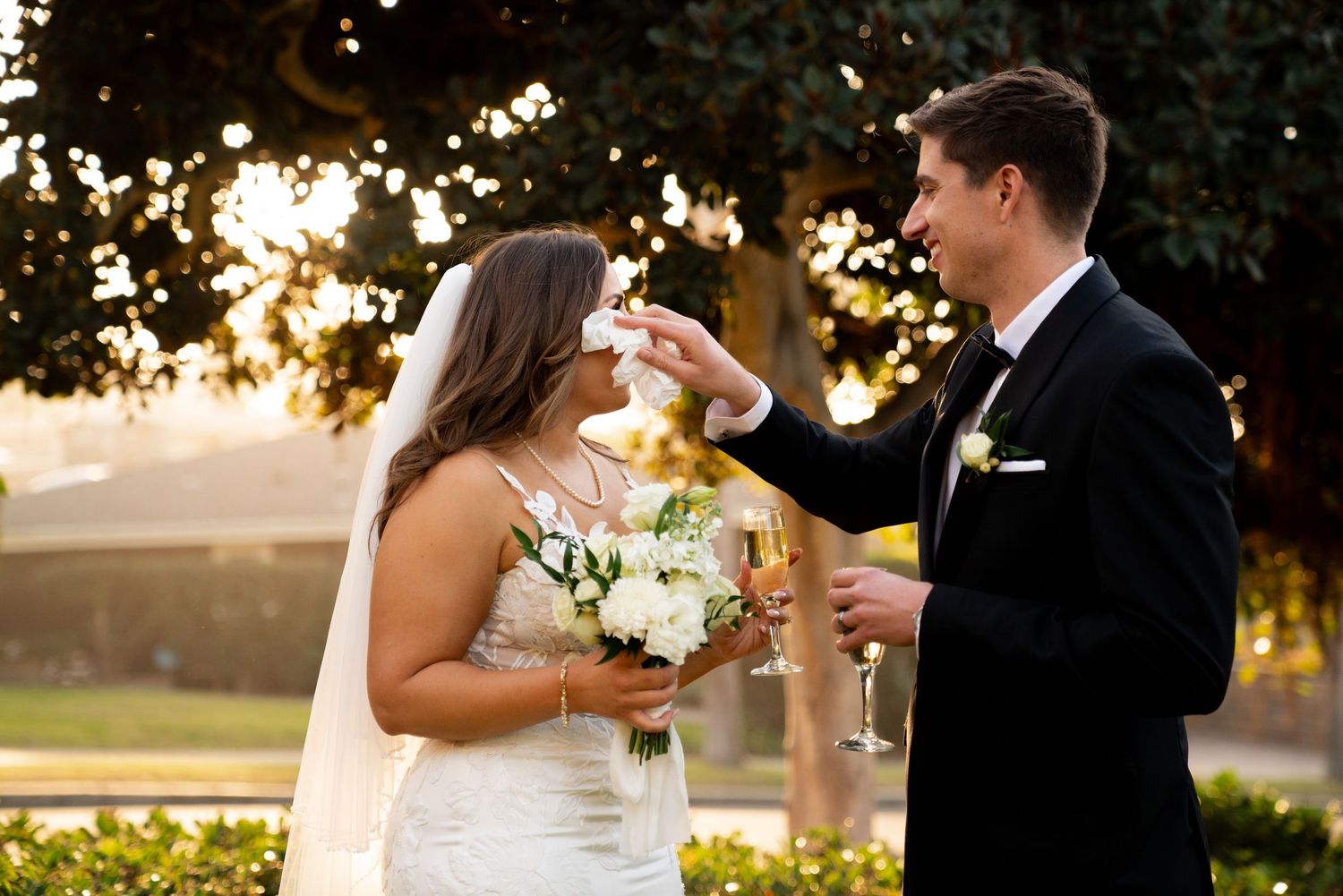 A couple shares a playful moment with their wedding cake during sunset.