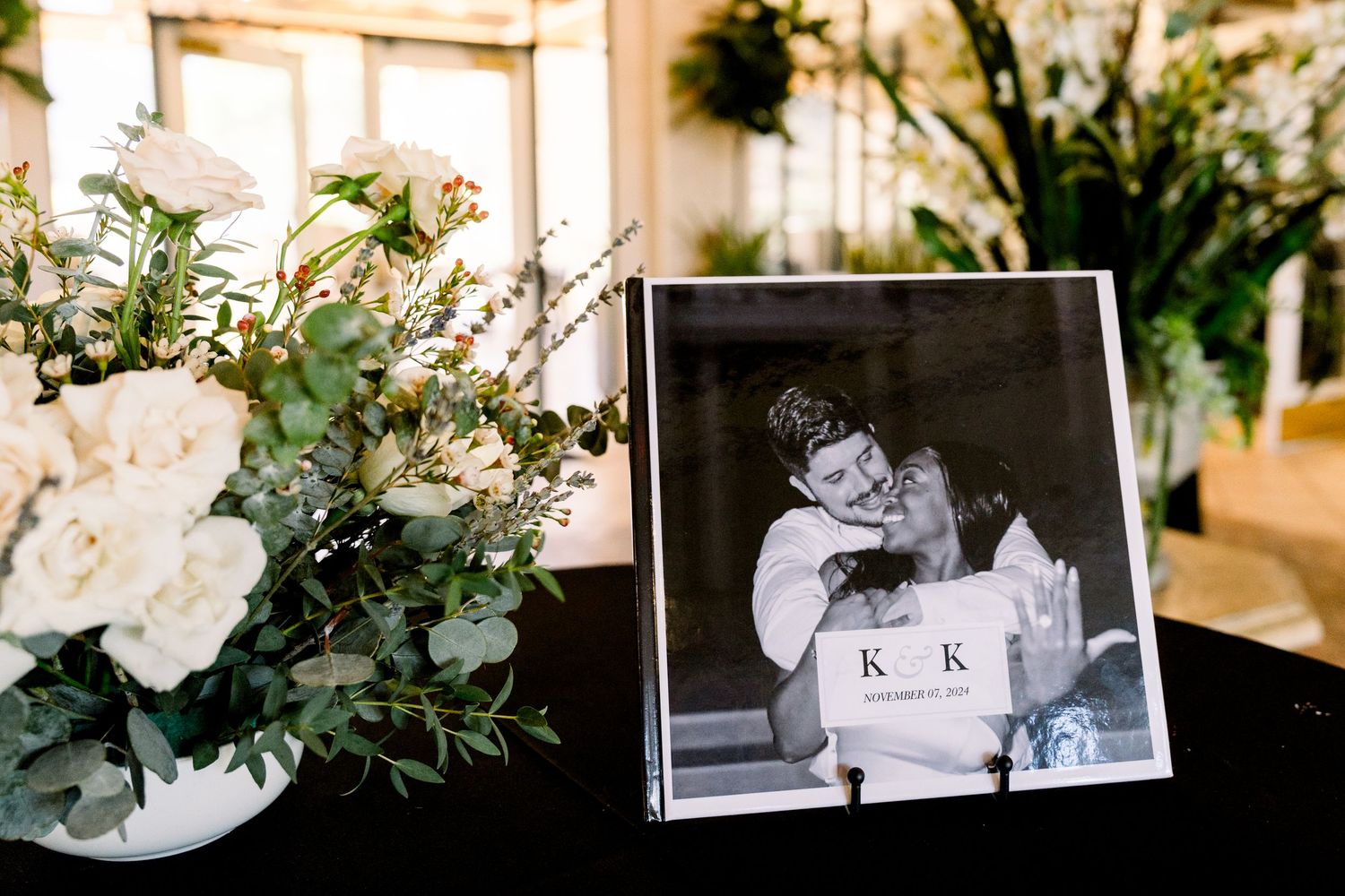 Vintage photograph displayed next to white floral arrangement at wedding reception.