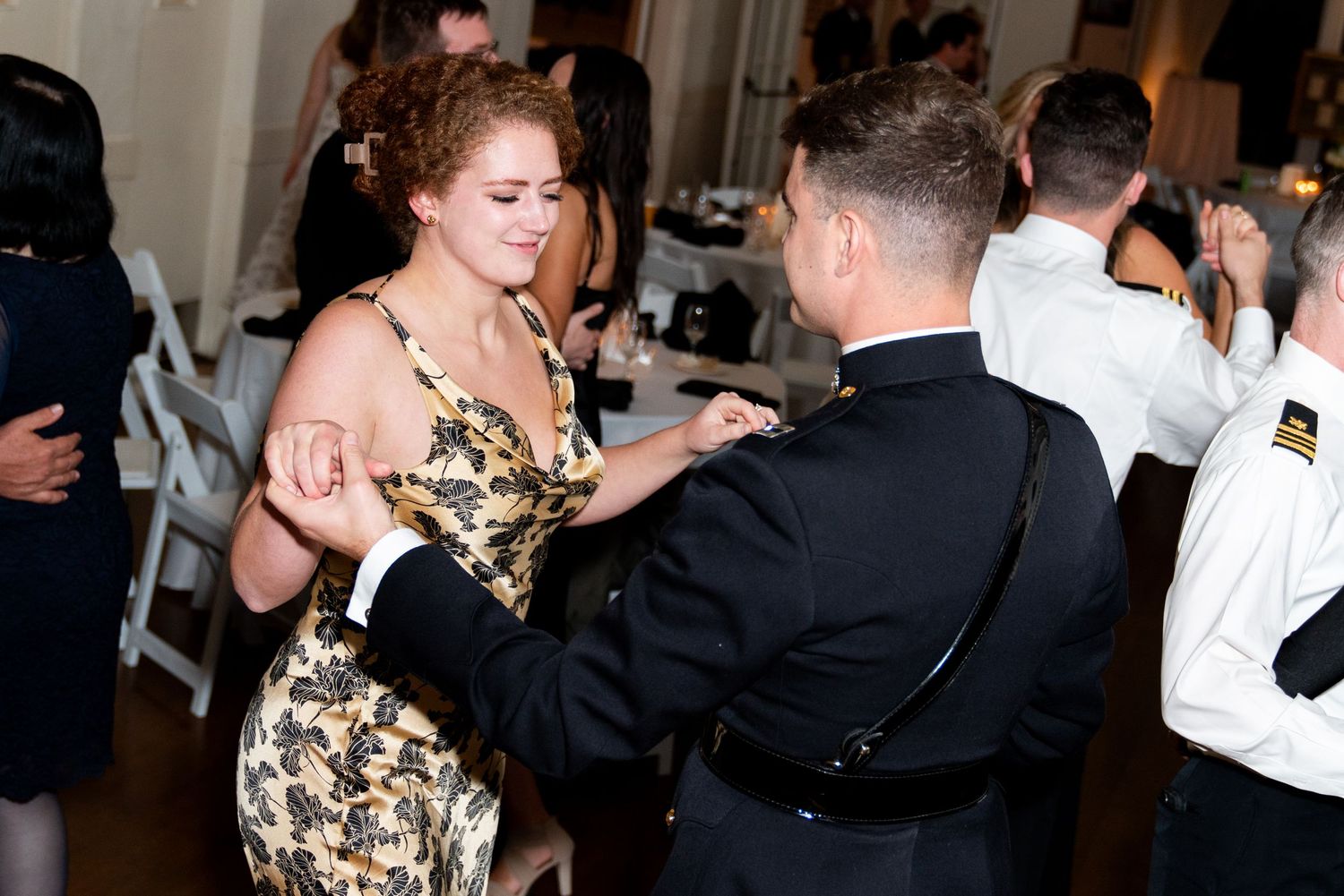 Couple dancing in formal attire at an elegant indoor reception venue.