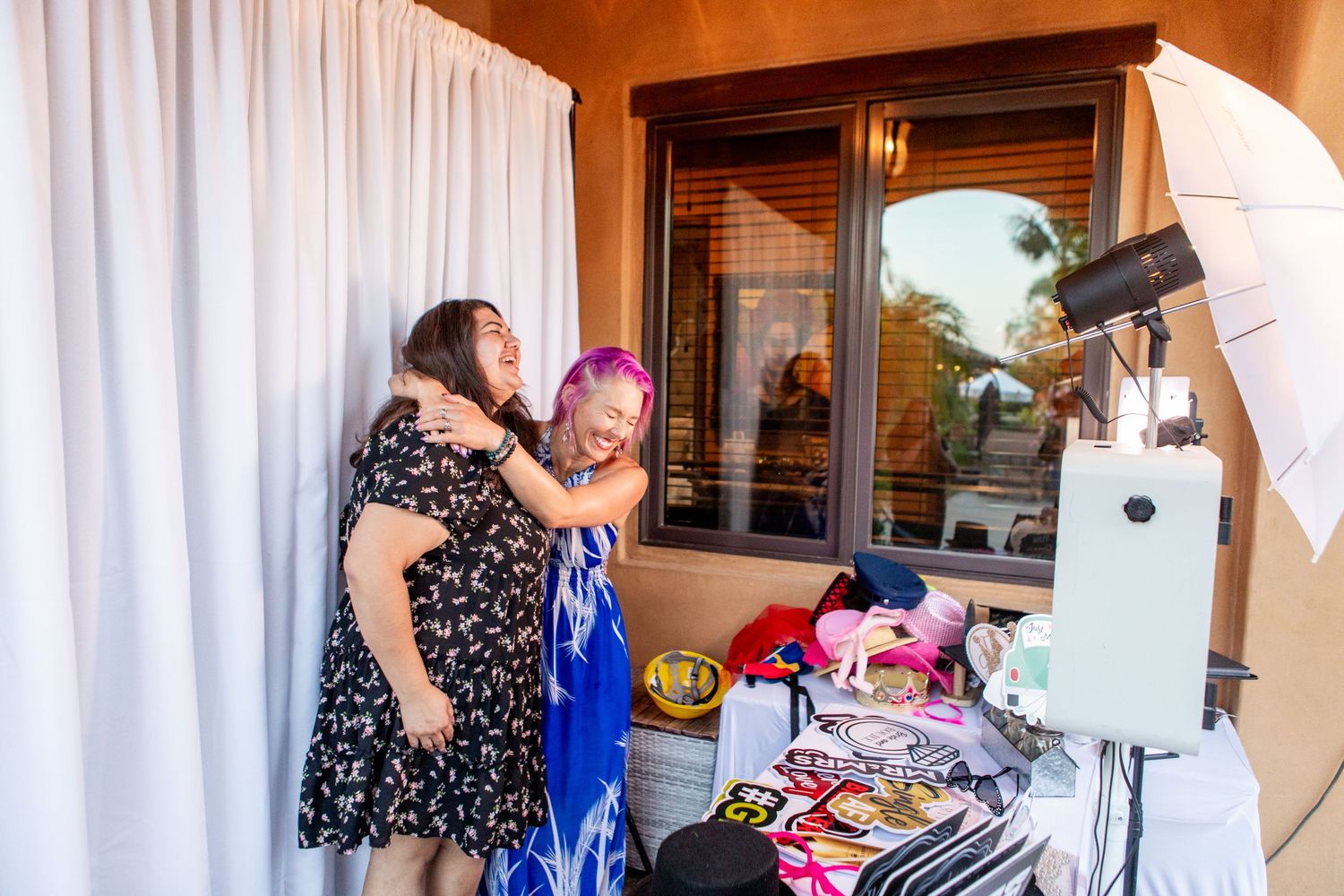 Guests enjoying a photo booth station with props at an outdoor wedding reception.