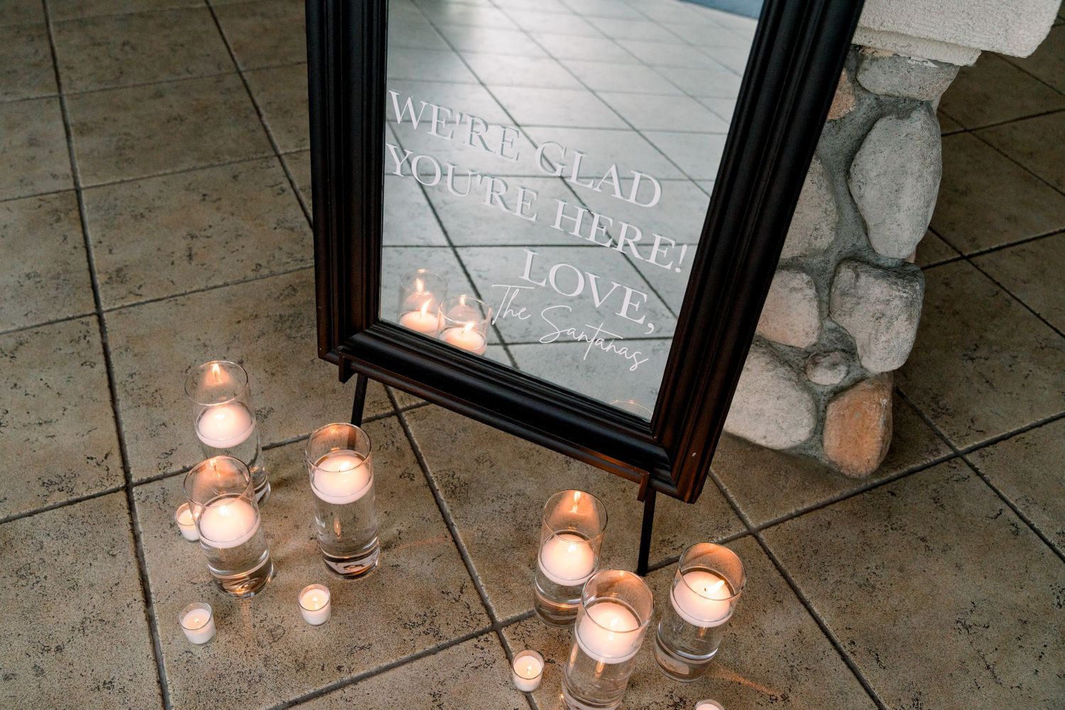 Romantic display of glowing candles arranged around a dark framed mirror.