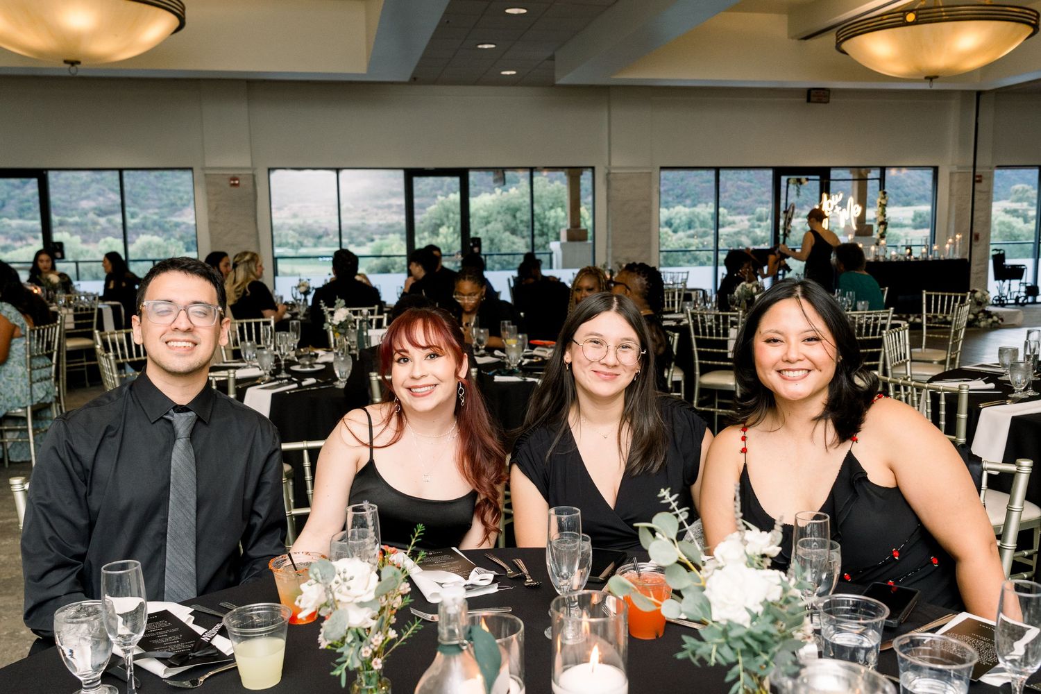 Wedding reception guests seated at an elegant dining table with floral centerpieces.