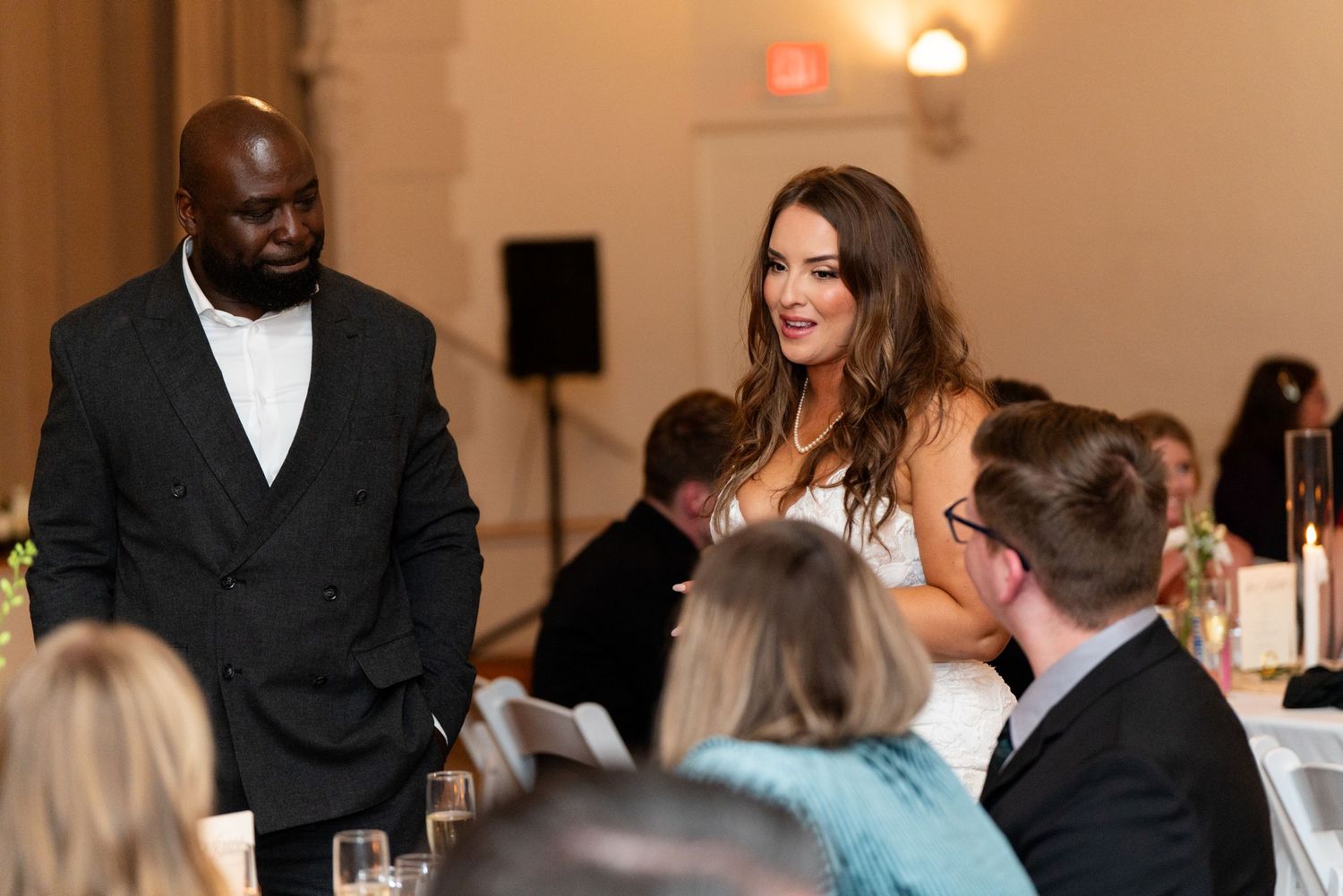 Wedding reception guests enjoying conversation and dinner at an indoor venue.