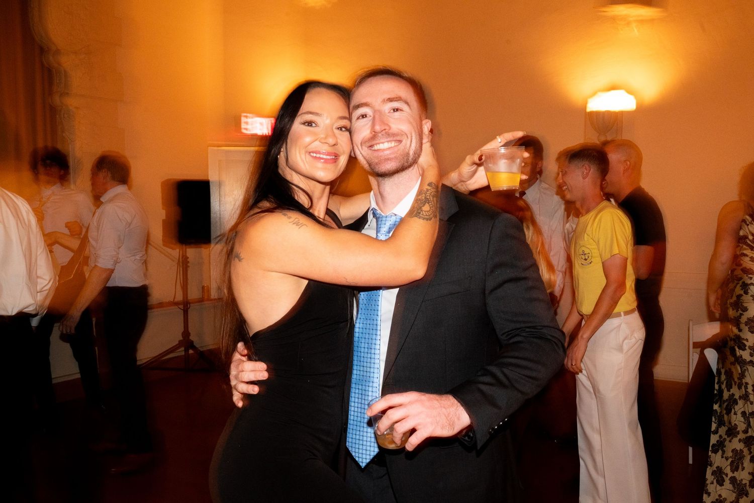 A couple dancing together at a celebration in warm lighting.