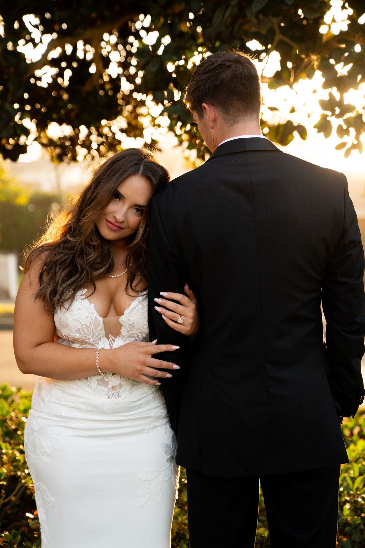 Romantic sunset portrait of a couple in wedding attire with golden light filtering through trees.