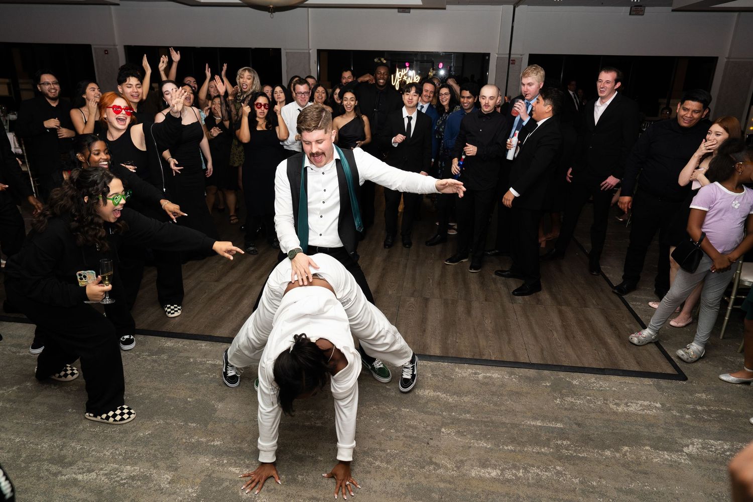 Energetic reception dance floor moment with guests cheering.