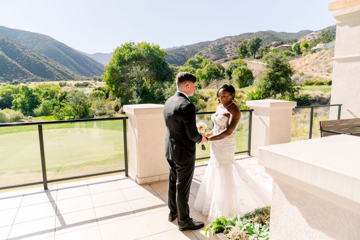 Couple sharing an intimate moment on a balcony overlooking mountain scenery.