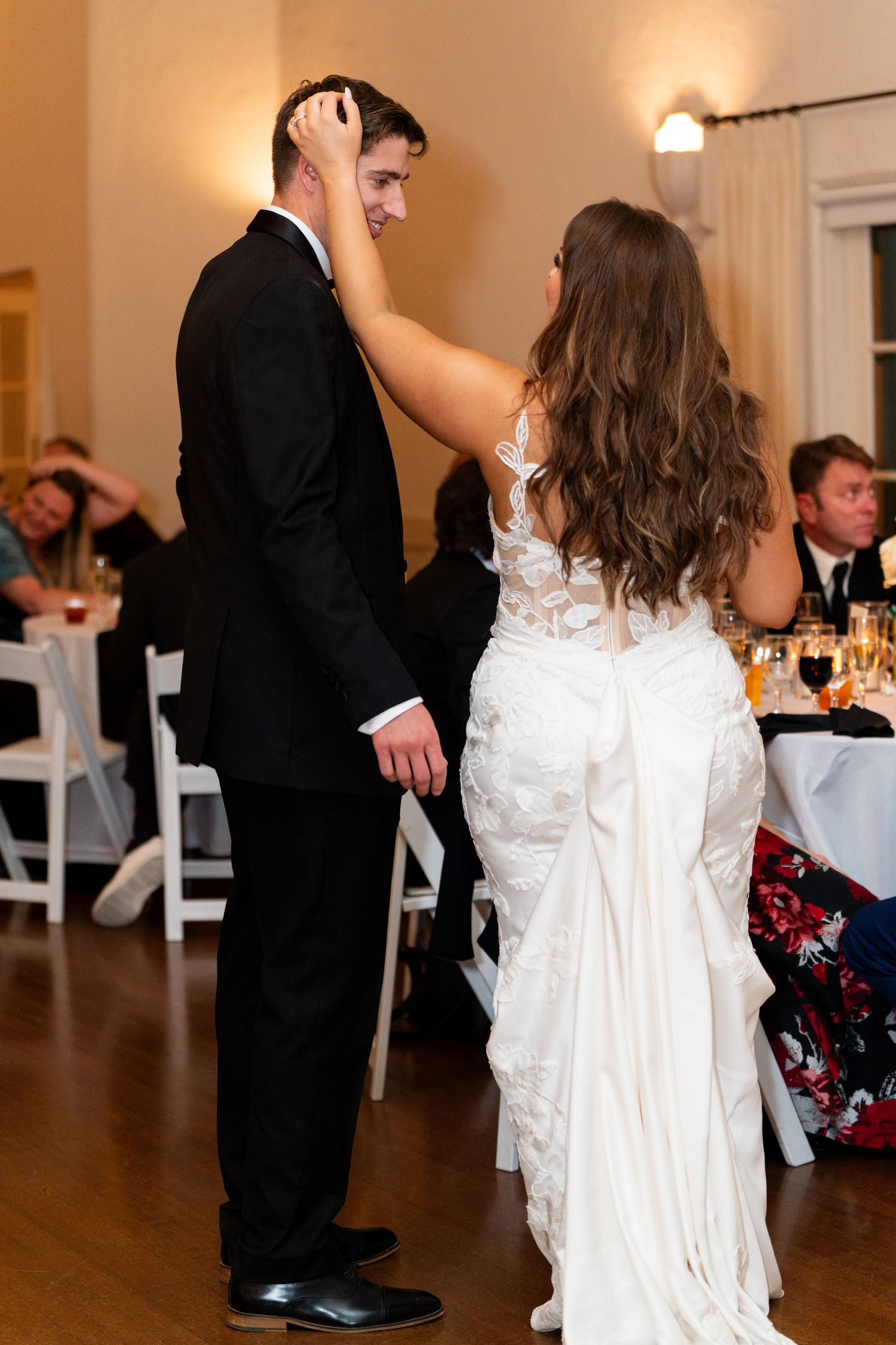 A couple shares an intimate dance moment at their wedding reception with the bride in a white gown.