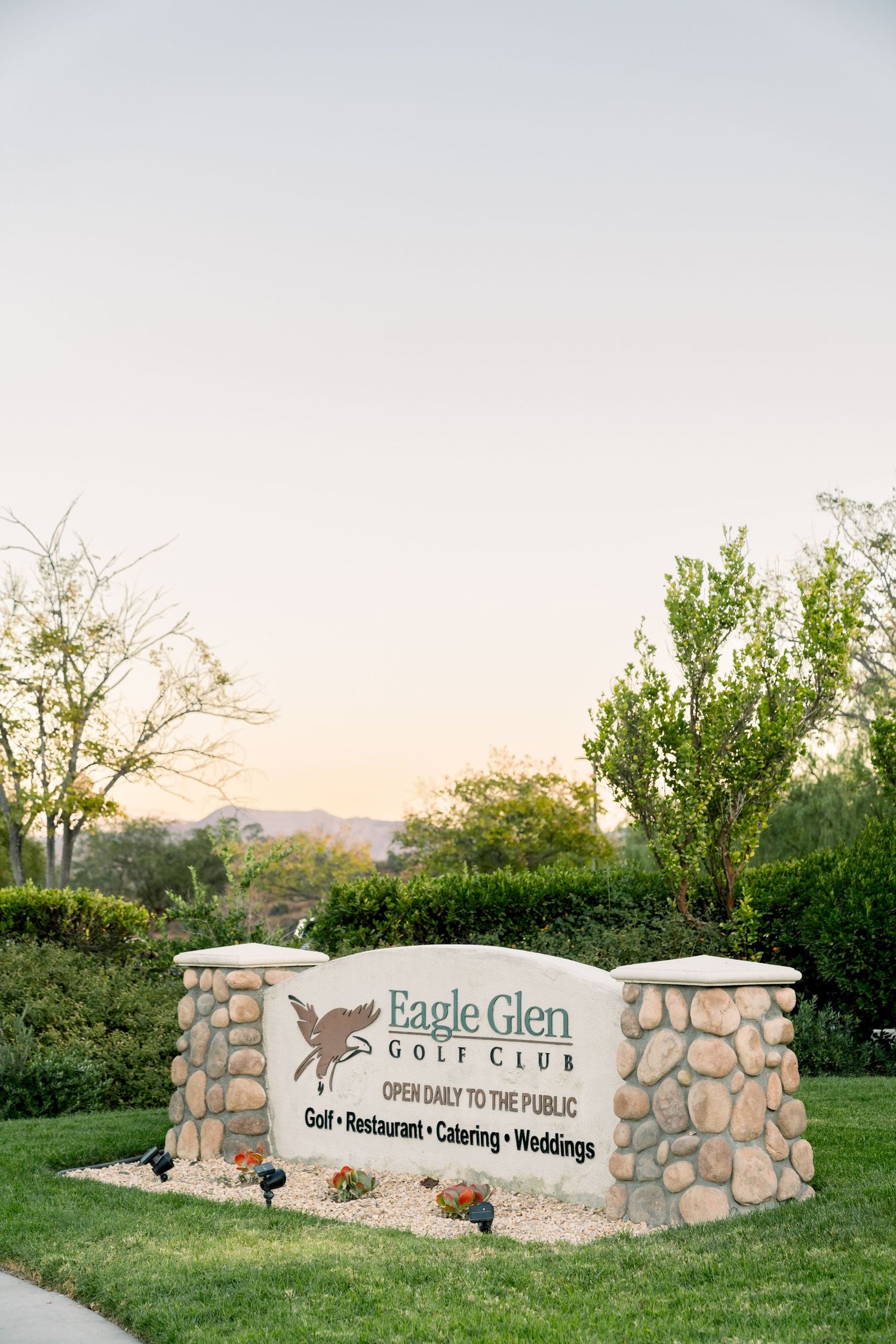 Eagle Glen Golf Club entrance sign with stone pillars at sunset.