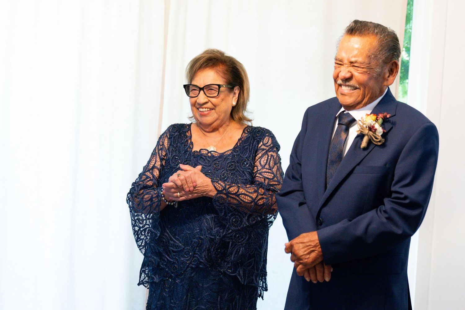 An elegant mature couple sharing a joyful laugh during a formal event in evening attire.