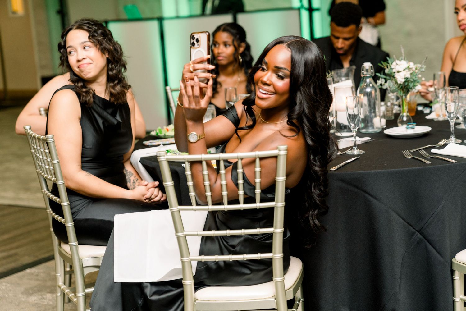 Reception guests enjoying dinner and conversation at tables with black linens.