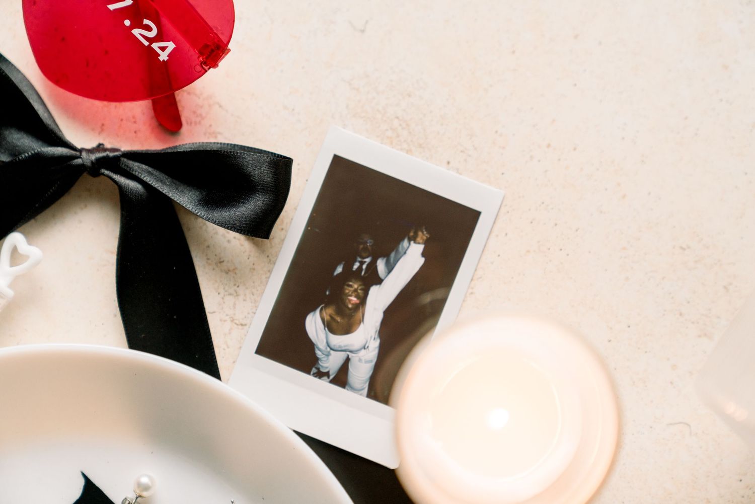 Still life with red balloon, black ribbon, polaroid photo and candle.