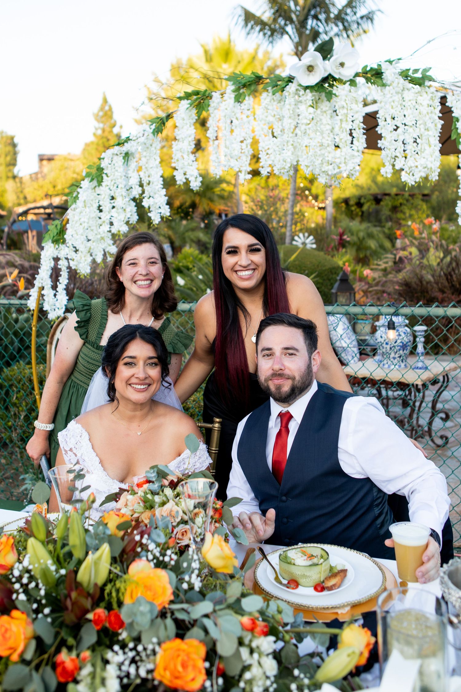 Wedding celebration under a floral arch with cascading white flowers and bright yellow accents.