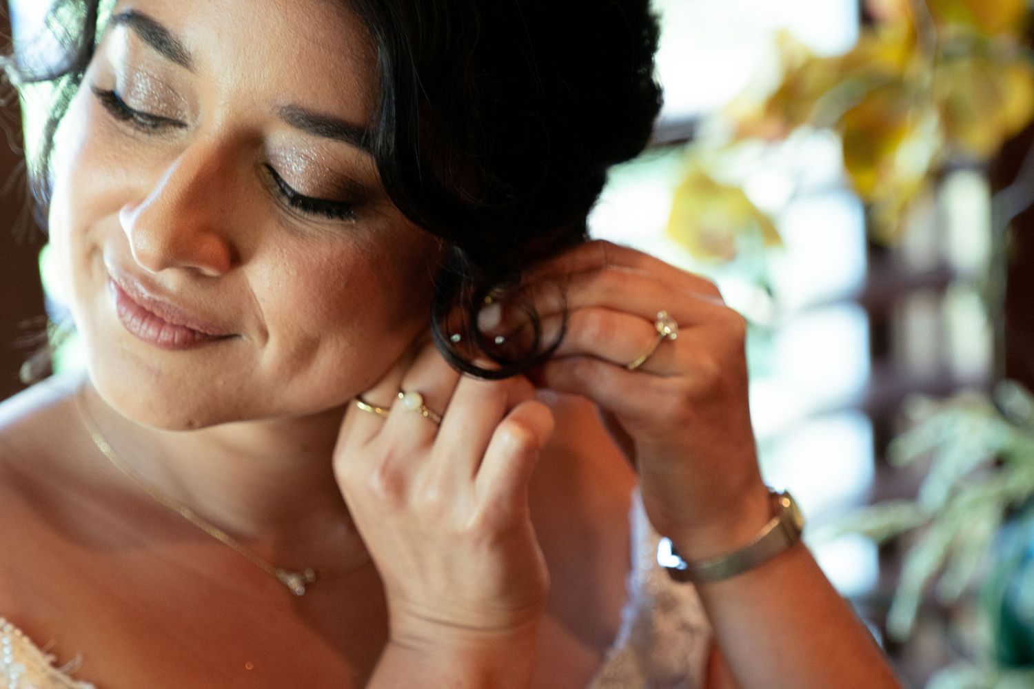 Close-up shot of someone putting on earrings while getting ready for a special occasion.