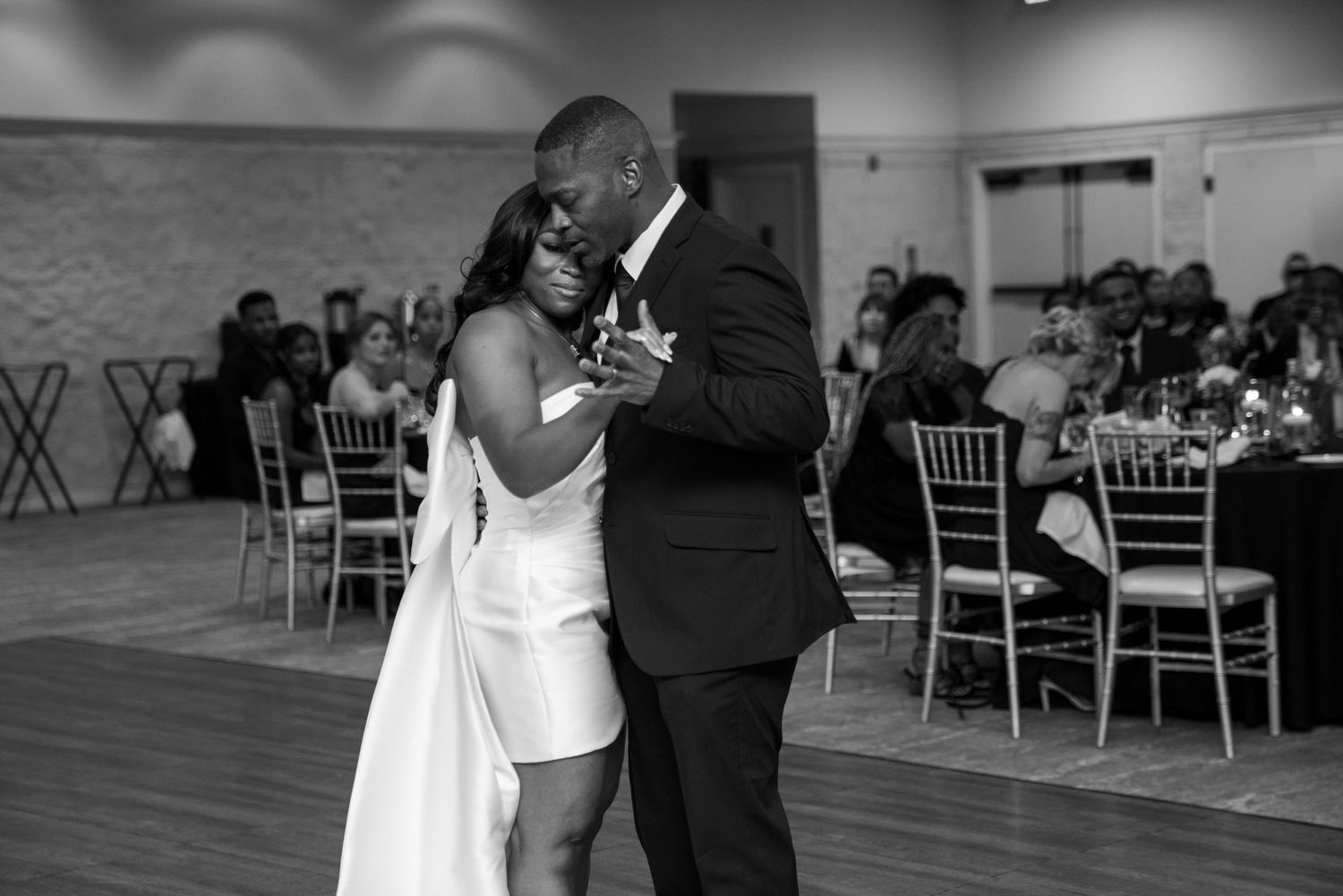 Couple sharing intimate dance moment during indoor wedding reception.
