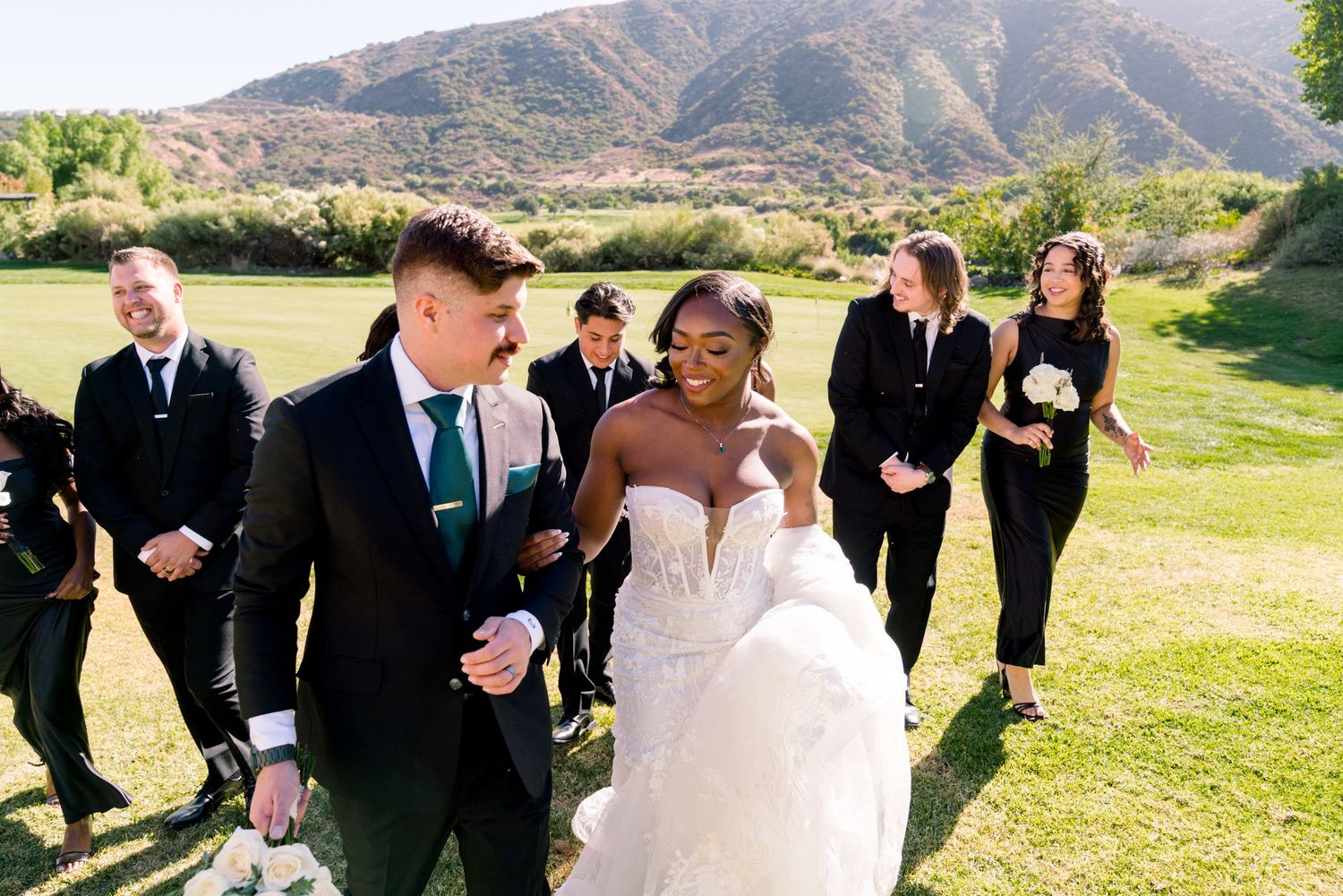 Wedding party walking together outdoors with mountains in the background.