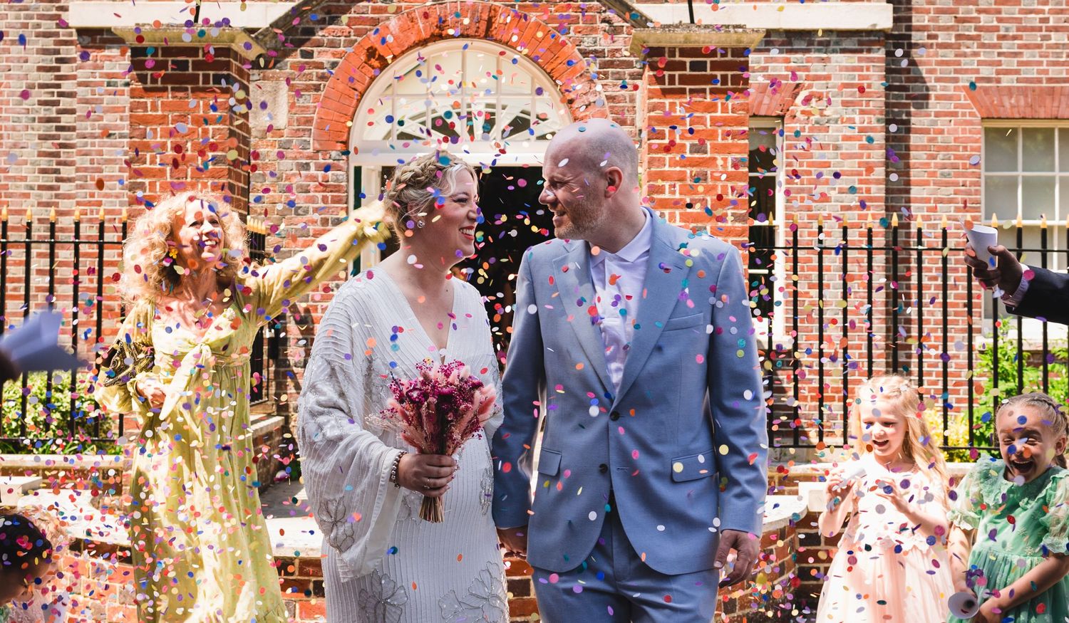 Couple smiling under confetti outside Portsmouth Registry office