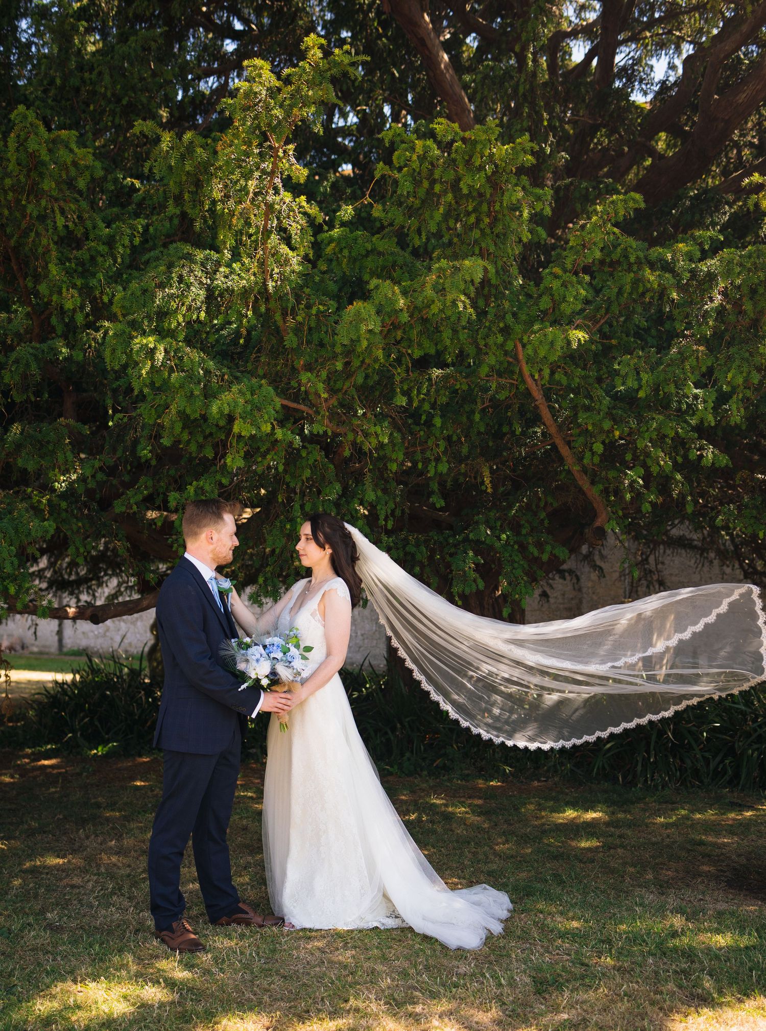 bride and groom standing outside under tree