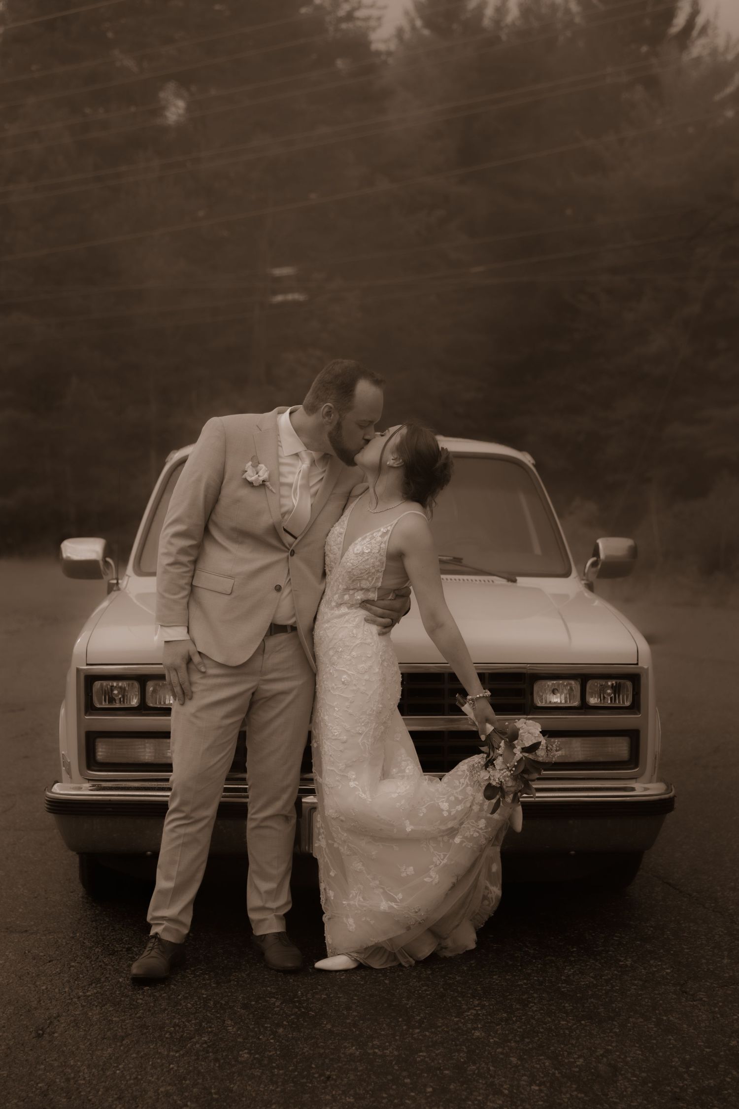 Romantic sepia portrait of newlyweds posing against a classic suburban truck.