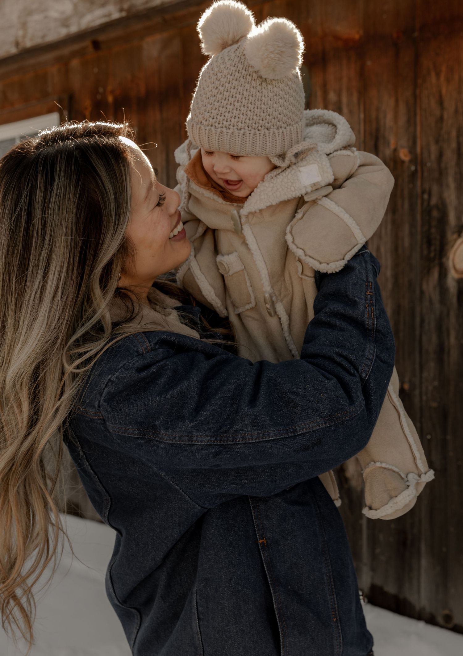 A tender winter moment captured outdoors showing affection between parent and child wearing cozy cold weather clothing.