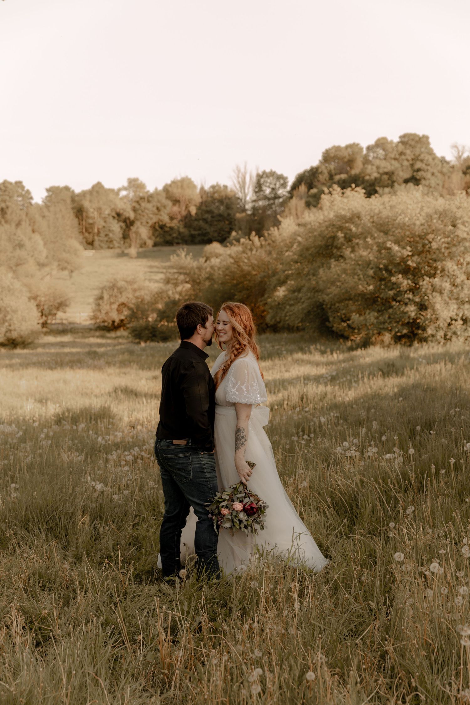 A romantic sunset wedding photo of a couple embracing in a golden meadow.