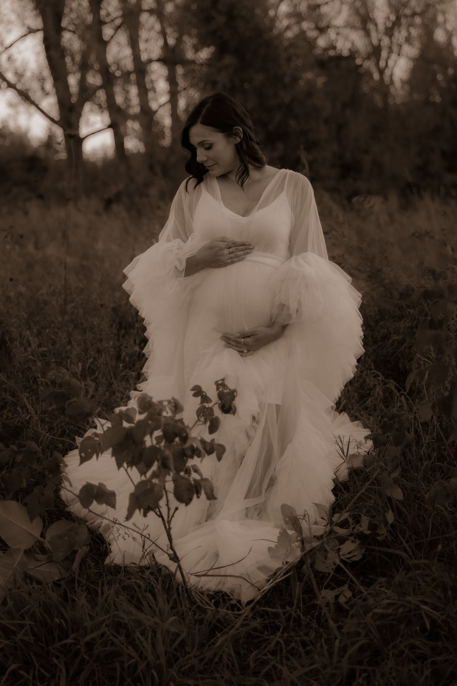 A flowing white gown creates an ethereal silhouette in a dreamy sepia-toned field.