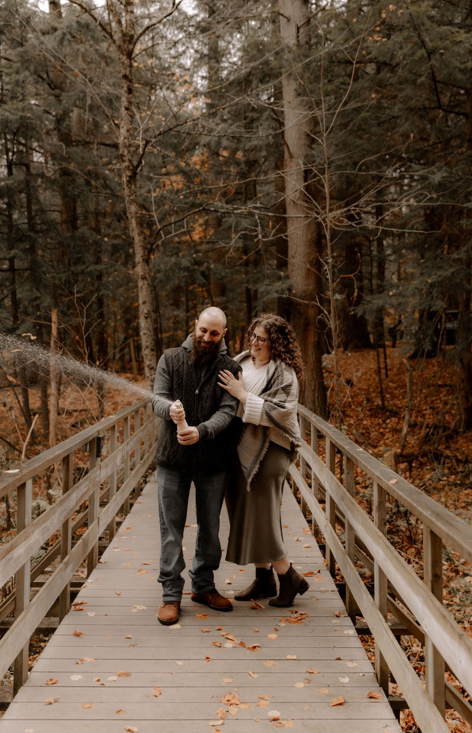 Couple sharing romantic moment while standing on wooden boardwalk in autumn forest.