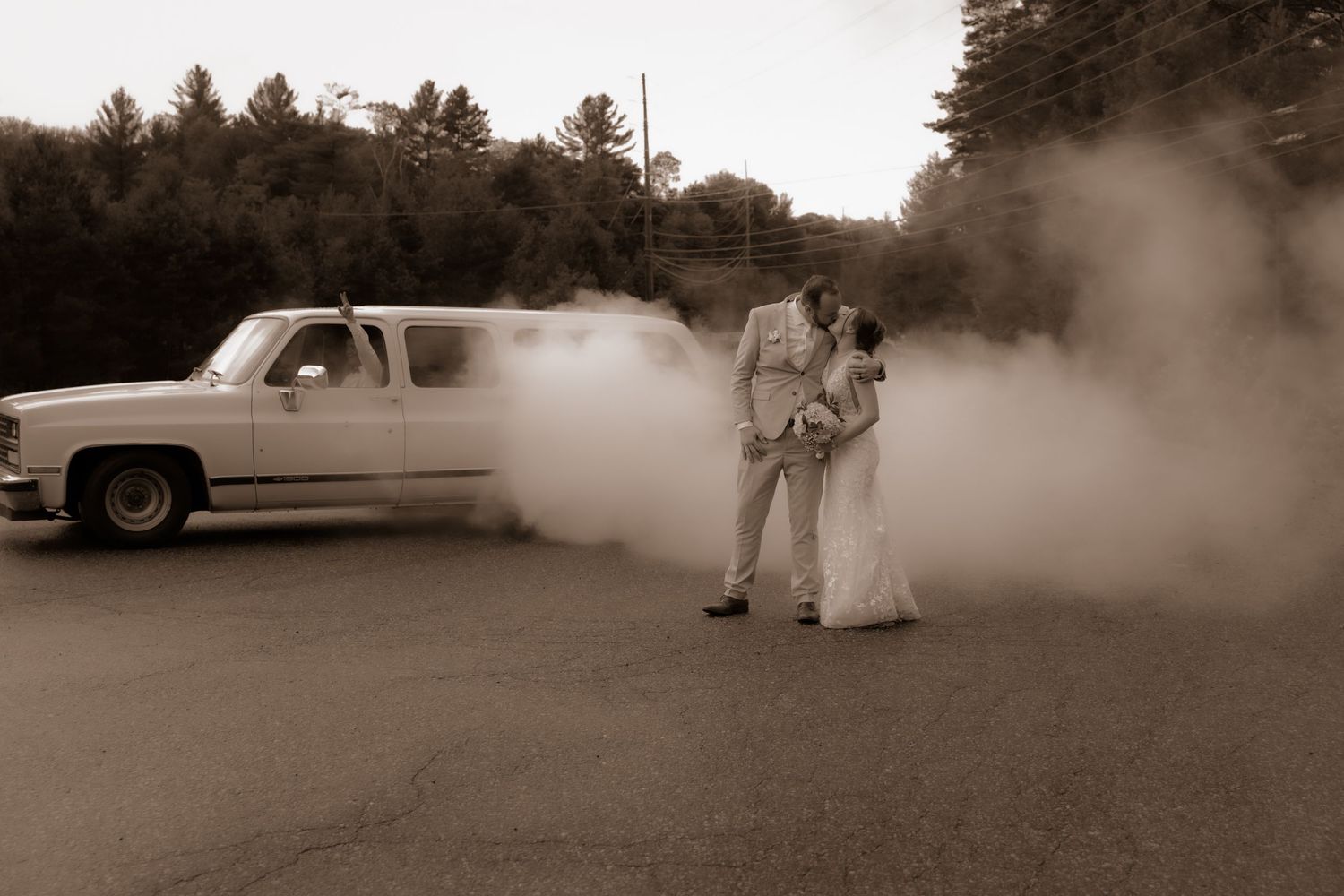 Sepia wedding photo with couple enveloped in smoke near classic pickup truck.