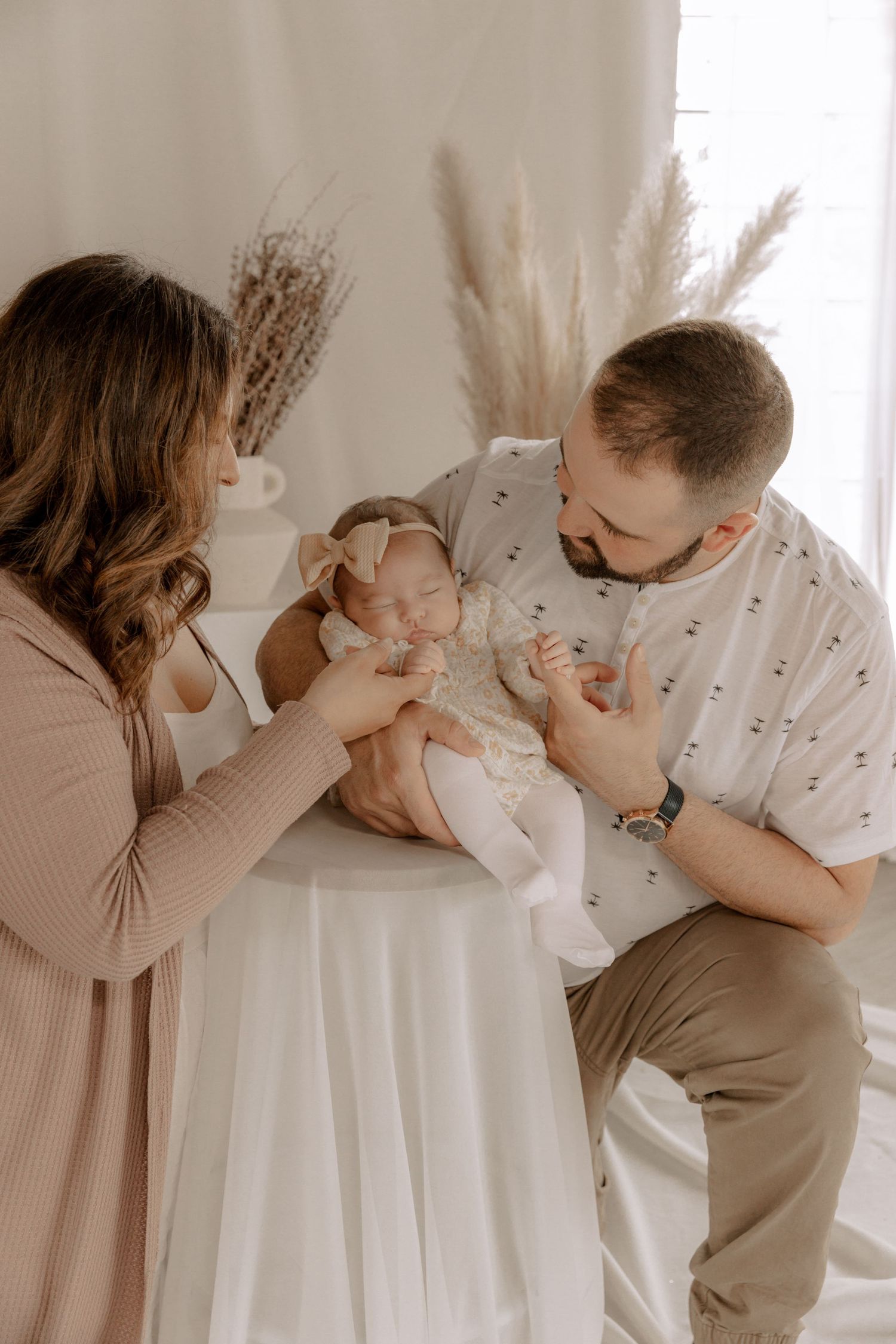A sweet family moment captured in soft lighting with pampas grass decor and neutral tones.