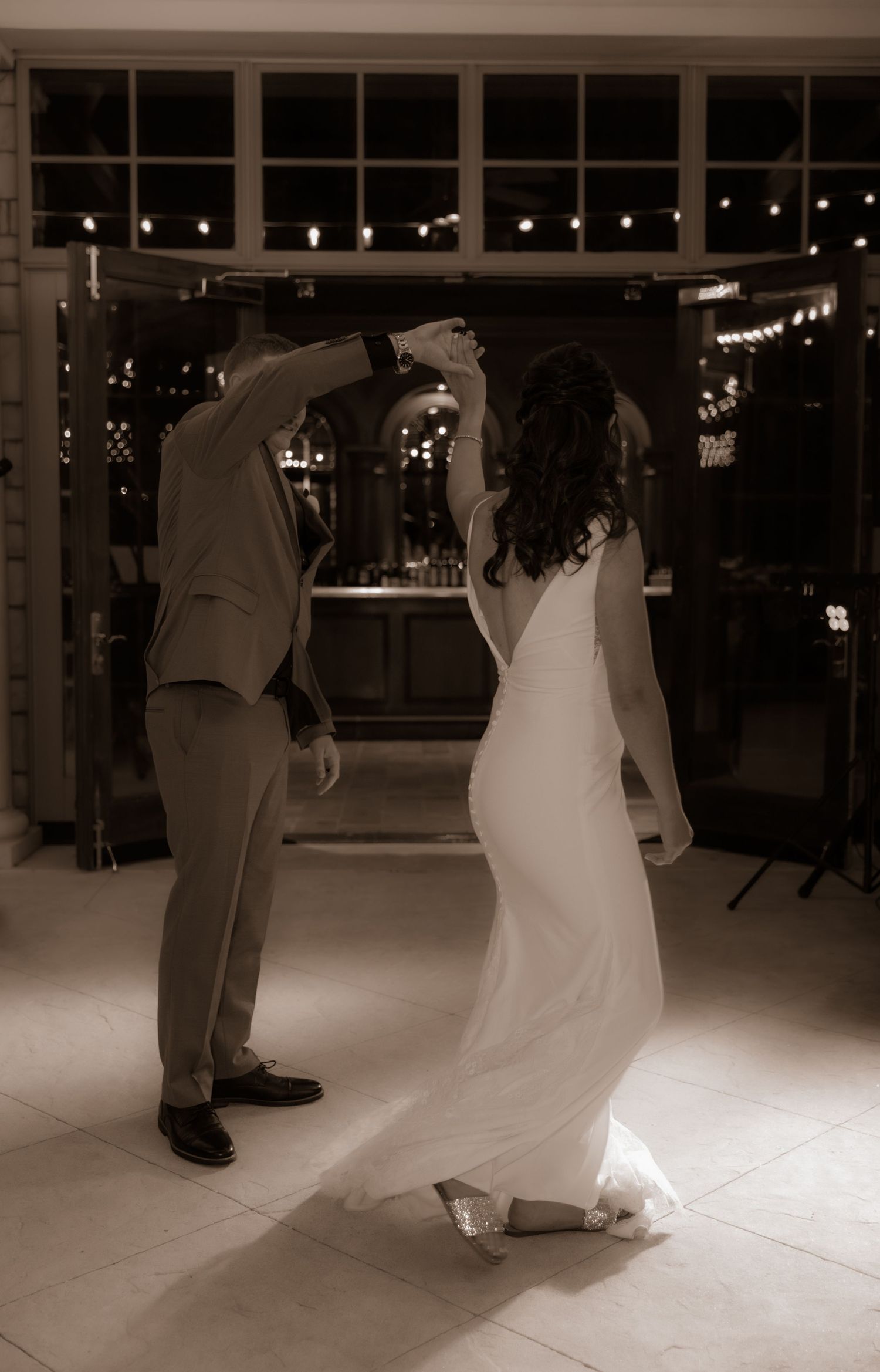 A couple dancing together at their wedding reception under romantic lighting.