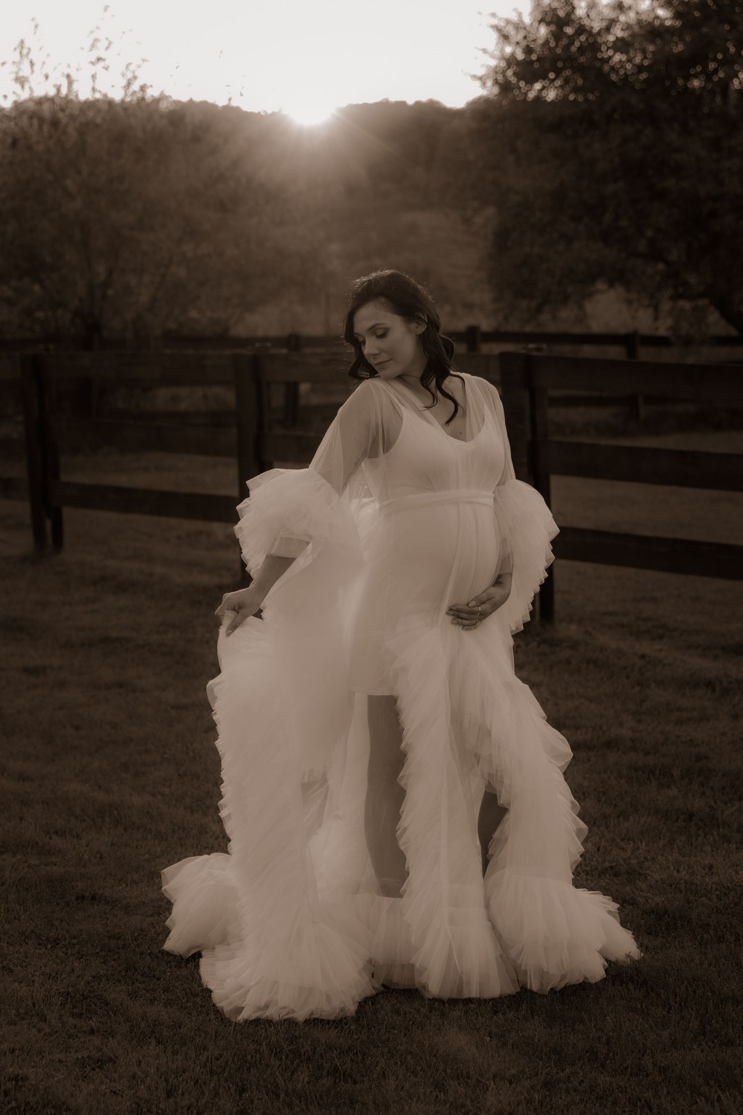 Dreamy sepia portrait of wedding dress with flowing tulle details at sunset.