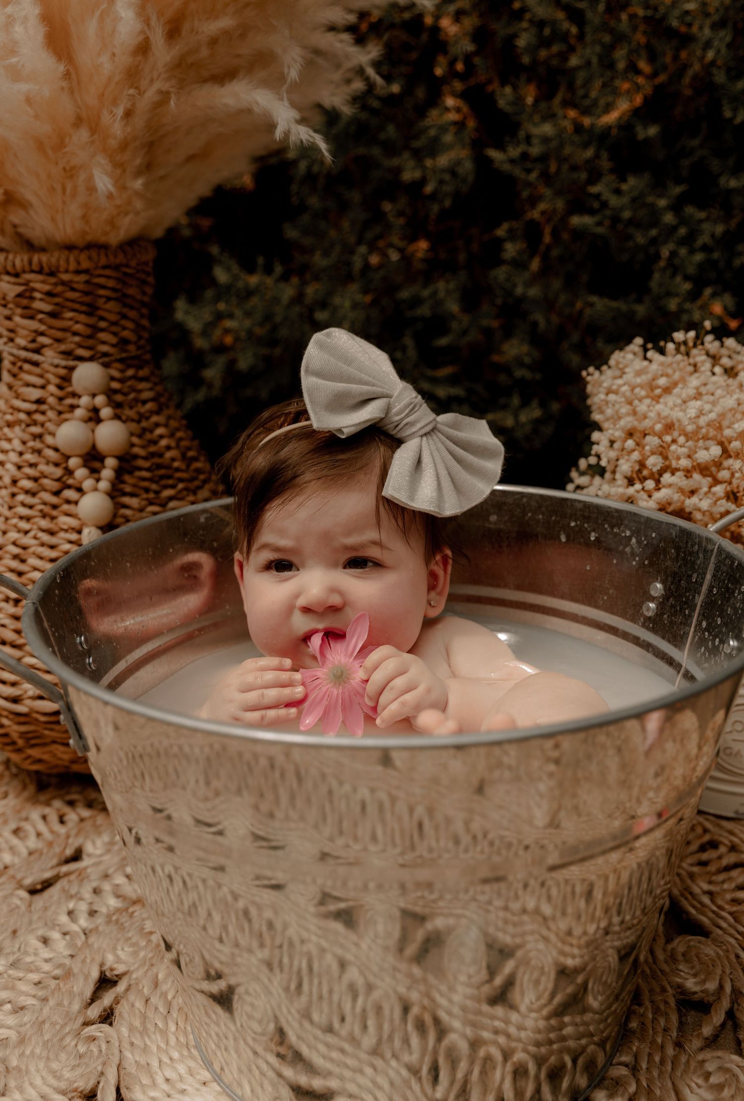 Small child in a milky bath inside ornate vintage metal tub during outdoor rustic photo session.