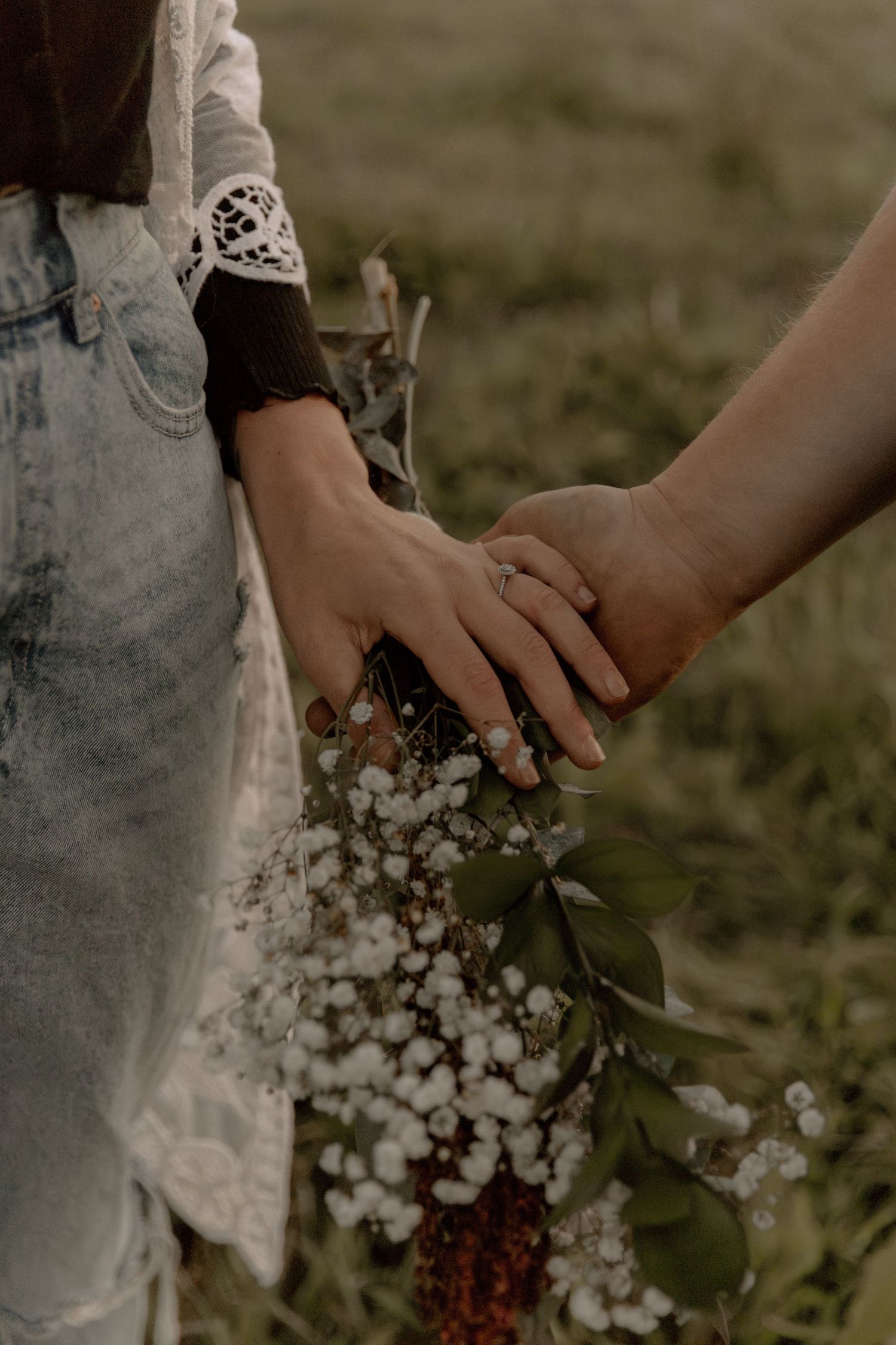 Gentle holding of hands with delicate lace sleeve detail and baby's breath flowers.