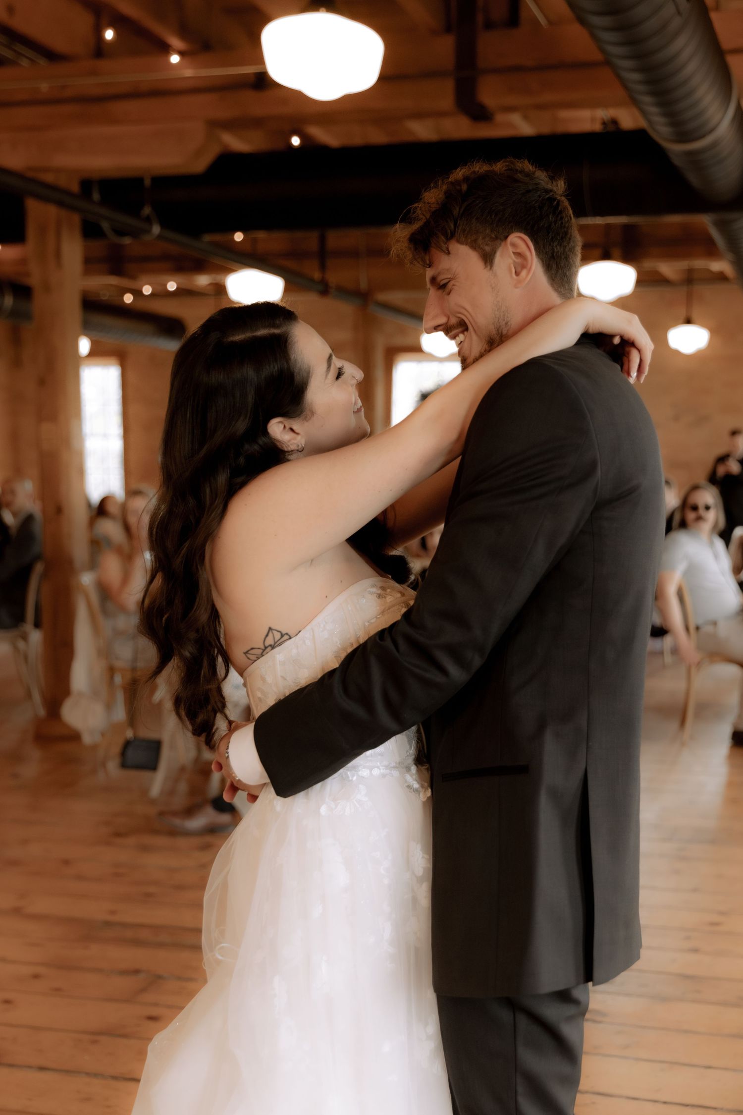 A tender moment between newlyweds during their first dance in an industrial-style reception venue.