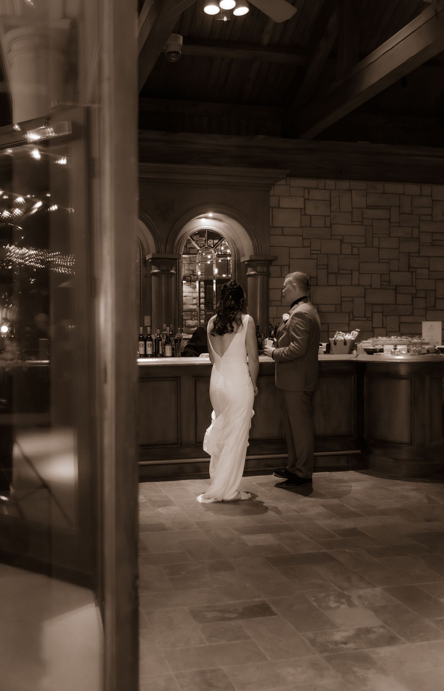 Couple sharing a moment at an elegant stone bar during their wedding reception.