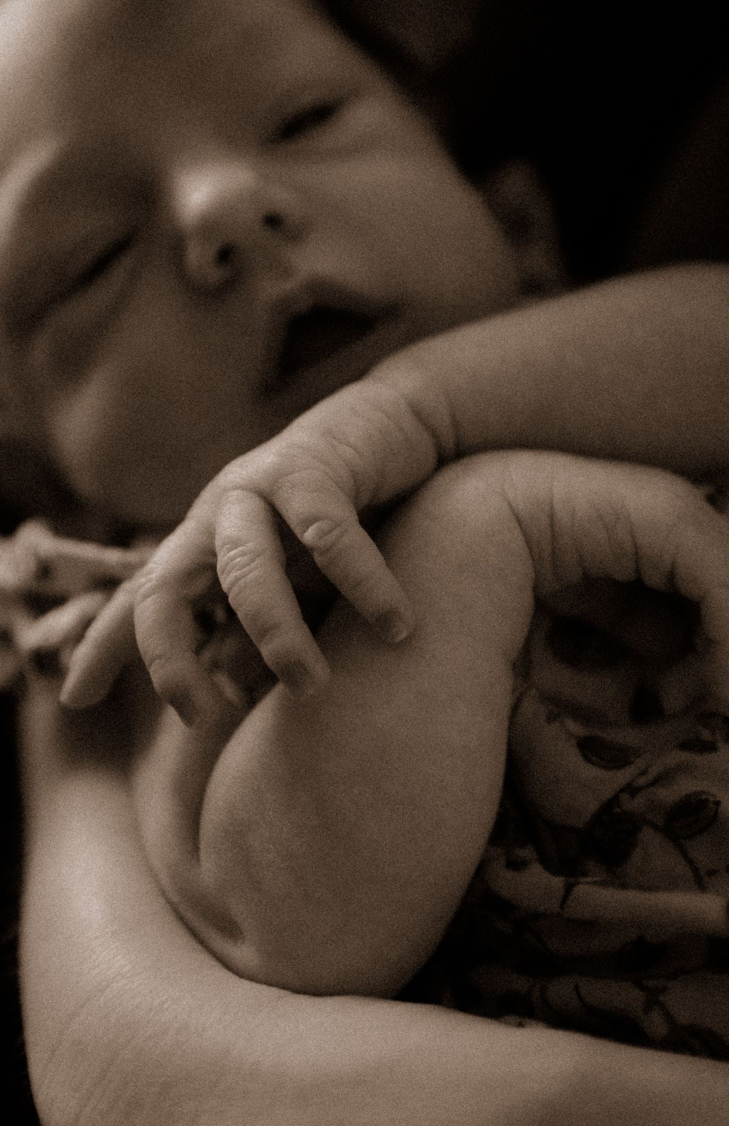 Artistic black and white capture of baby's hand and arm.