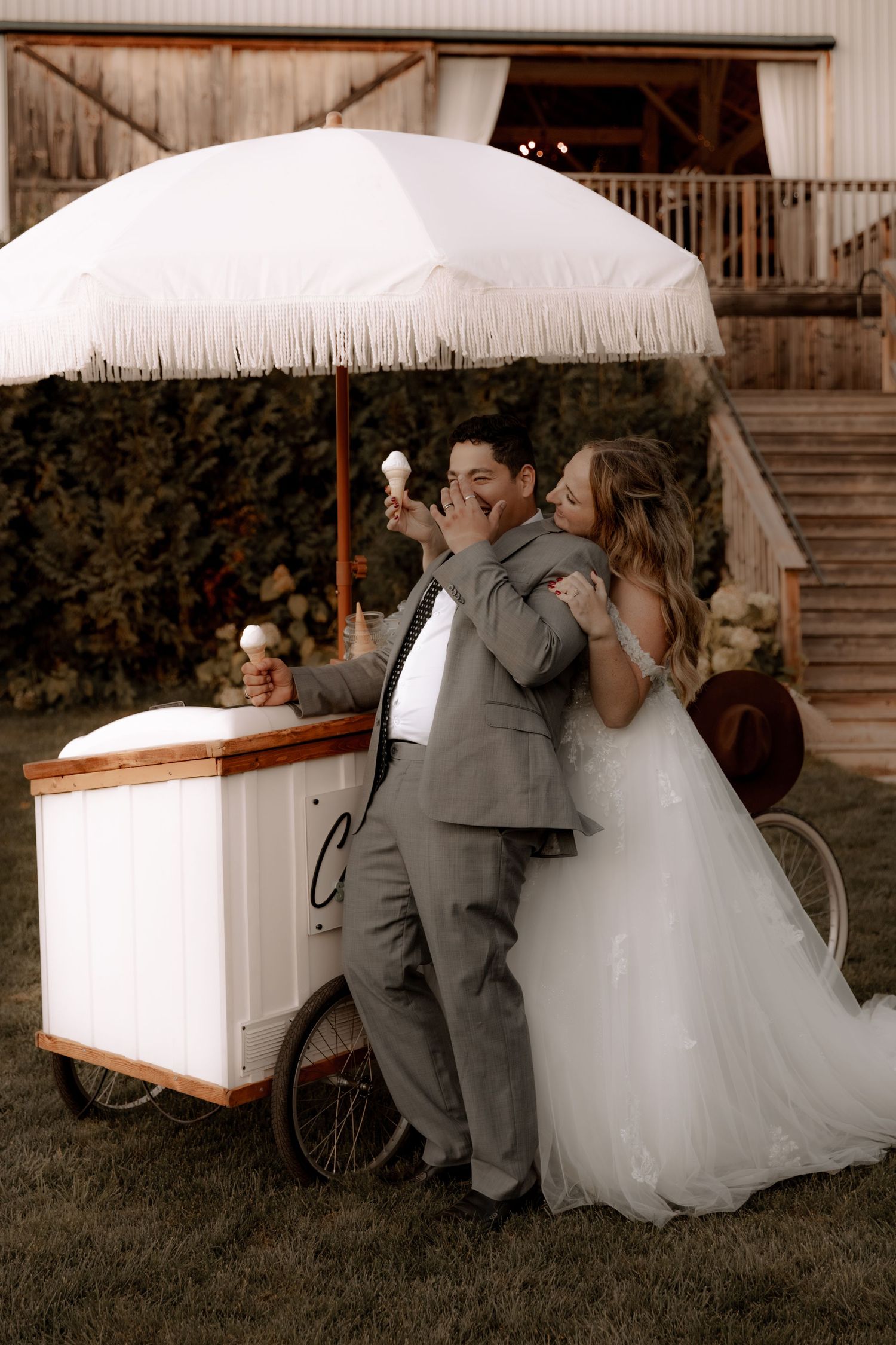 A joyful wedding moment at an ice cream cart featuring a bride and groom enjoying treats.