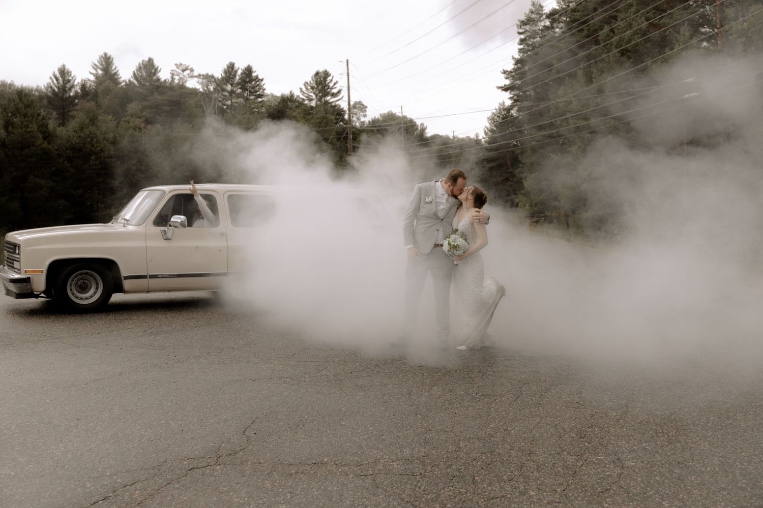 Black and white photo of a romantic moment in a cloud of smoke with a vintage truck in the background.
