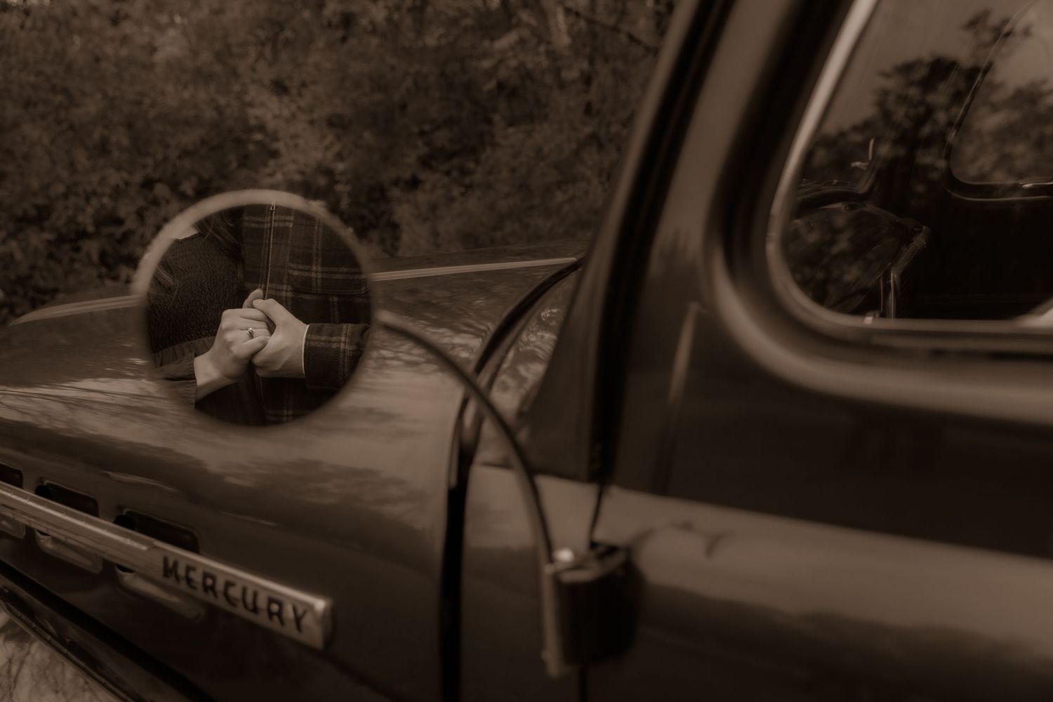 Vintage Mercury truck side mirror and door detail in sepia tones showing nostalgic reflection.