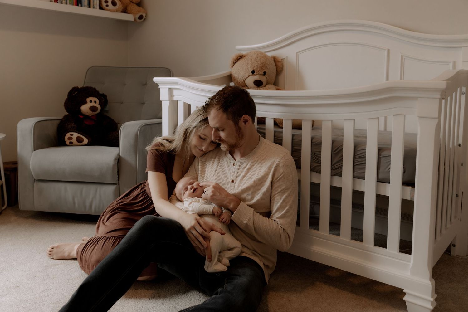 A tranquil nursery scene with a white crib, stuffed bear on a grey chair, and gentle lighting in warm sepia tones.